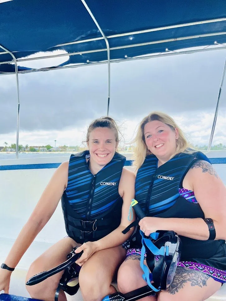 Two people wearing life jackets sitting on a boat.