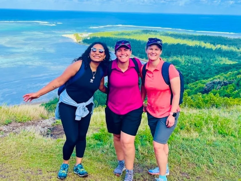Three women hiking with ocean and forest background