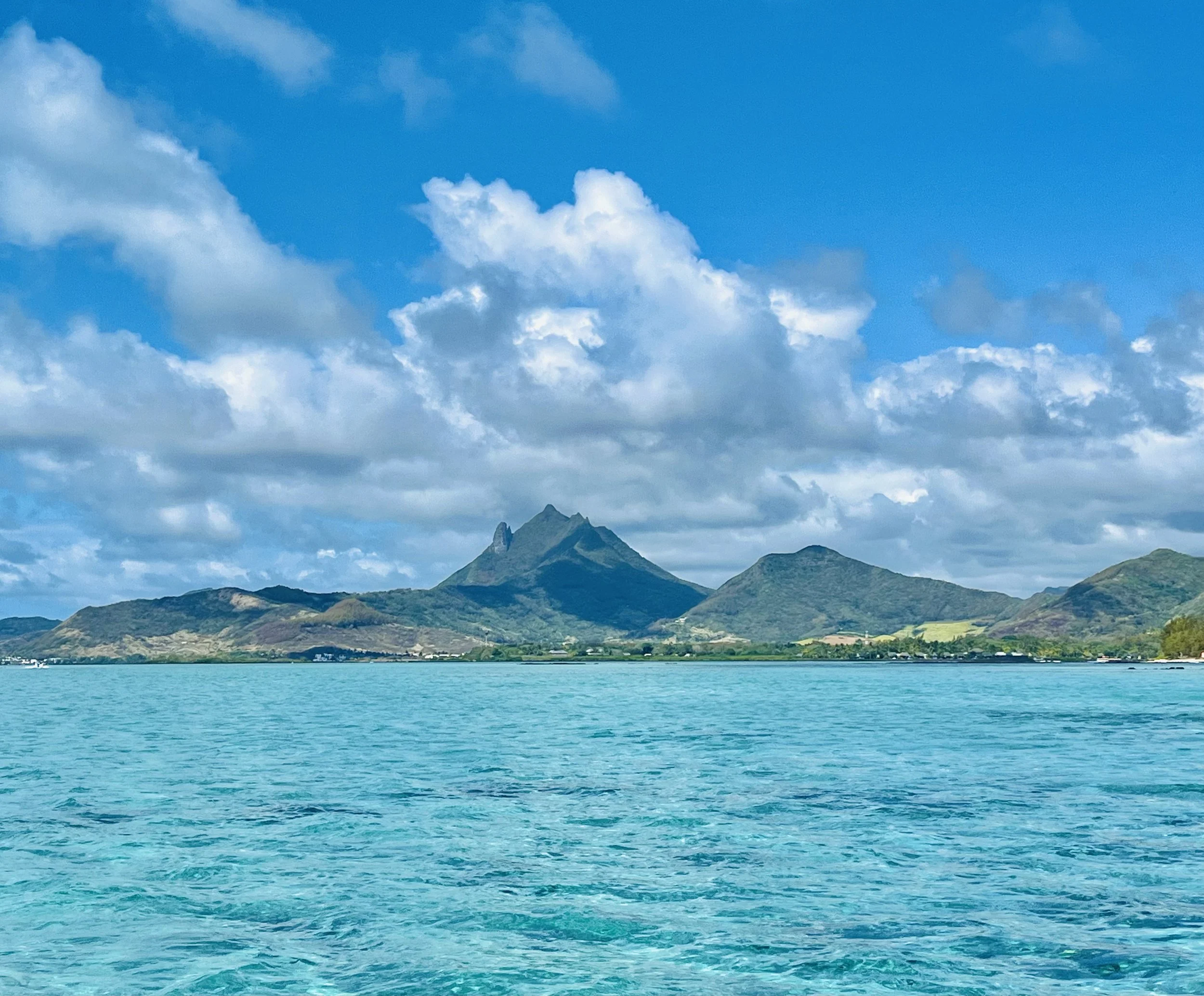 Blue sea with distant green hills and cloudy sky
