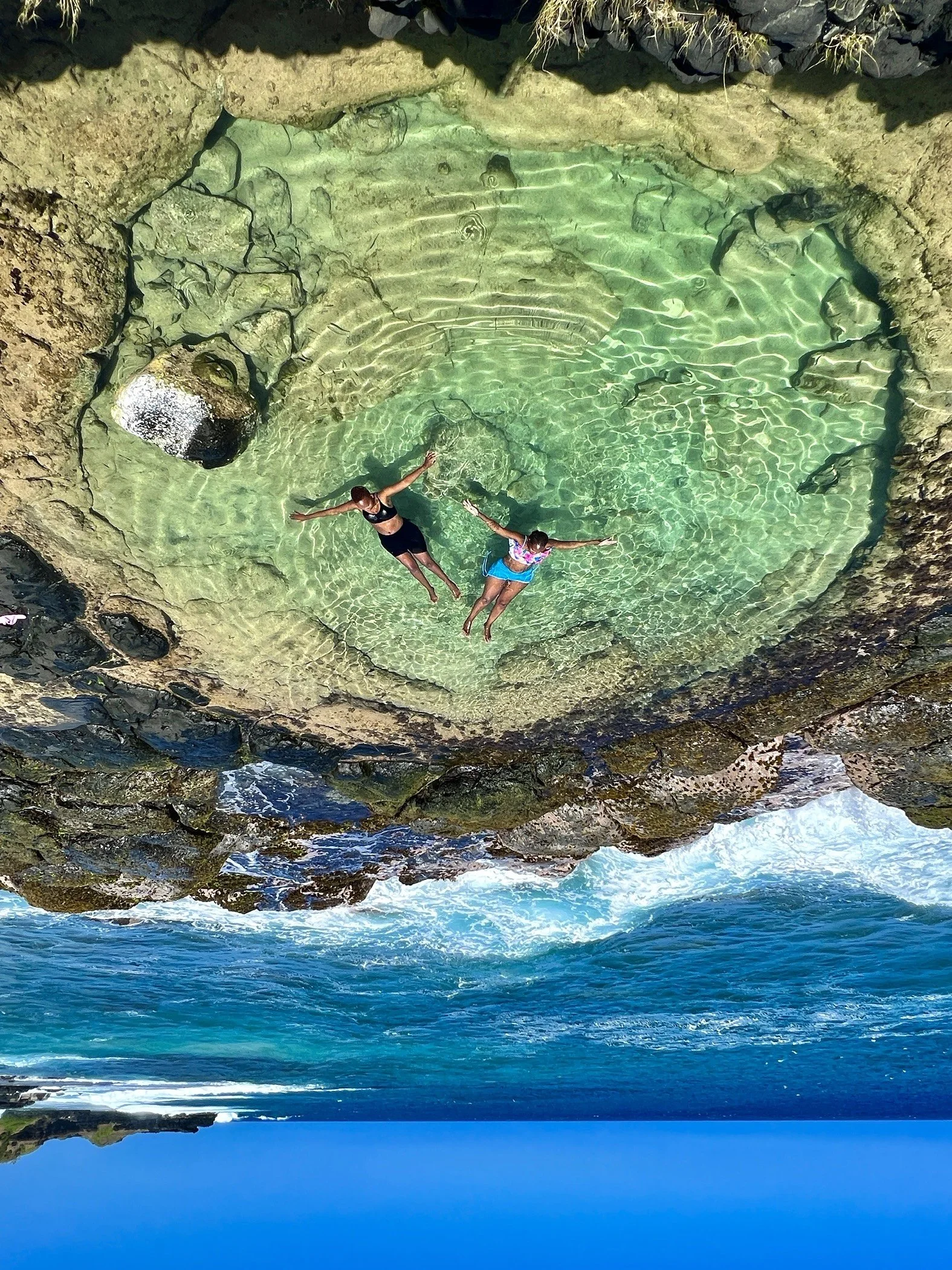 Two people floating in a natural tide pool by the ocean.