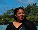 woman smiling outdoors near water and trees