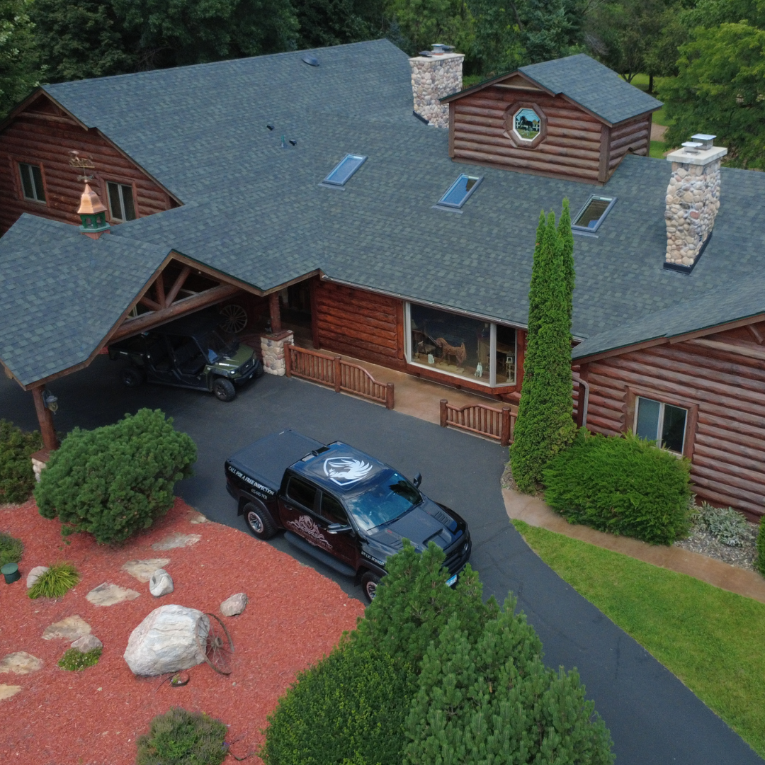 Citadel Construction completed asphalt shingle roof replacement on a log cabin home in Minnesota with skylights, stone chimneys, and gutters