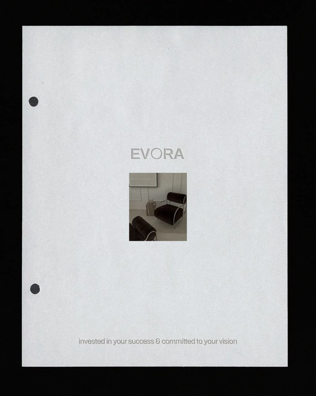 A white folder with three black binder rings on the left side, the word 'EVORA' embossed near the top, and a small photo of a black chair with a grey handbag nearby in the center. Text at the bottom reads, 'invested in your success & committed to your vision.'