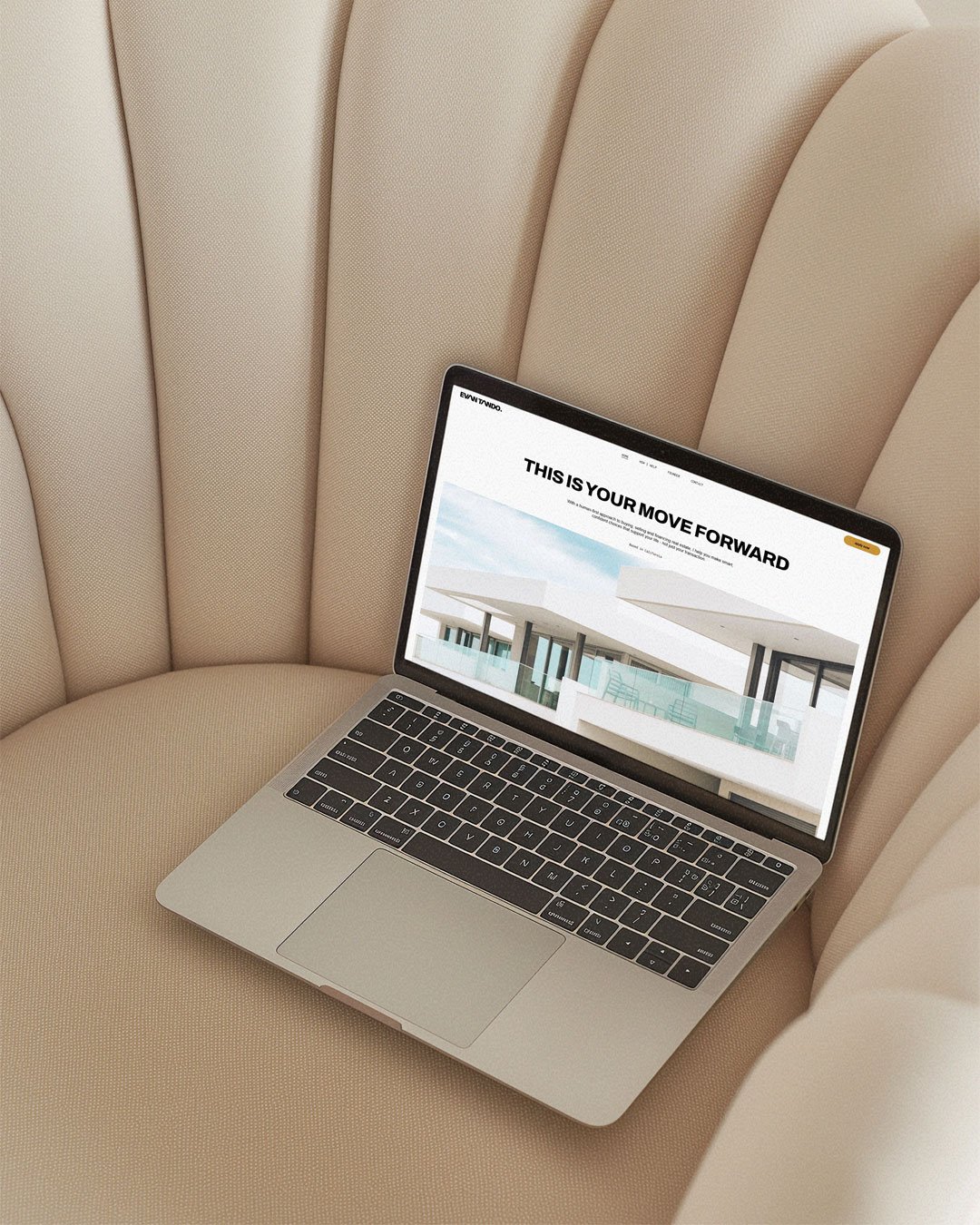 Open laptop on beige cushioned chair displaying a website with the headline "This is your move forward" and modern architecture images.