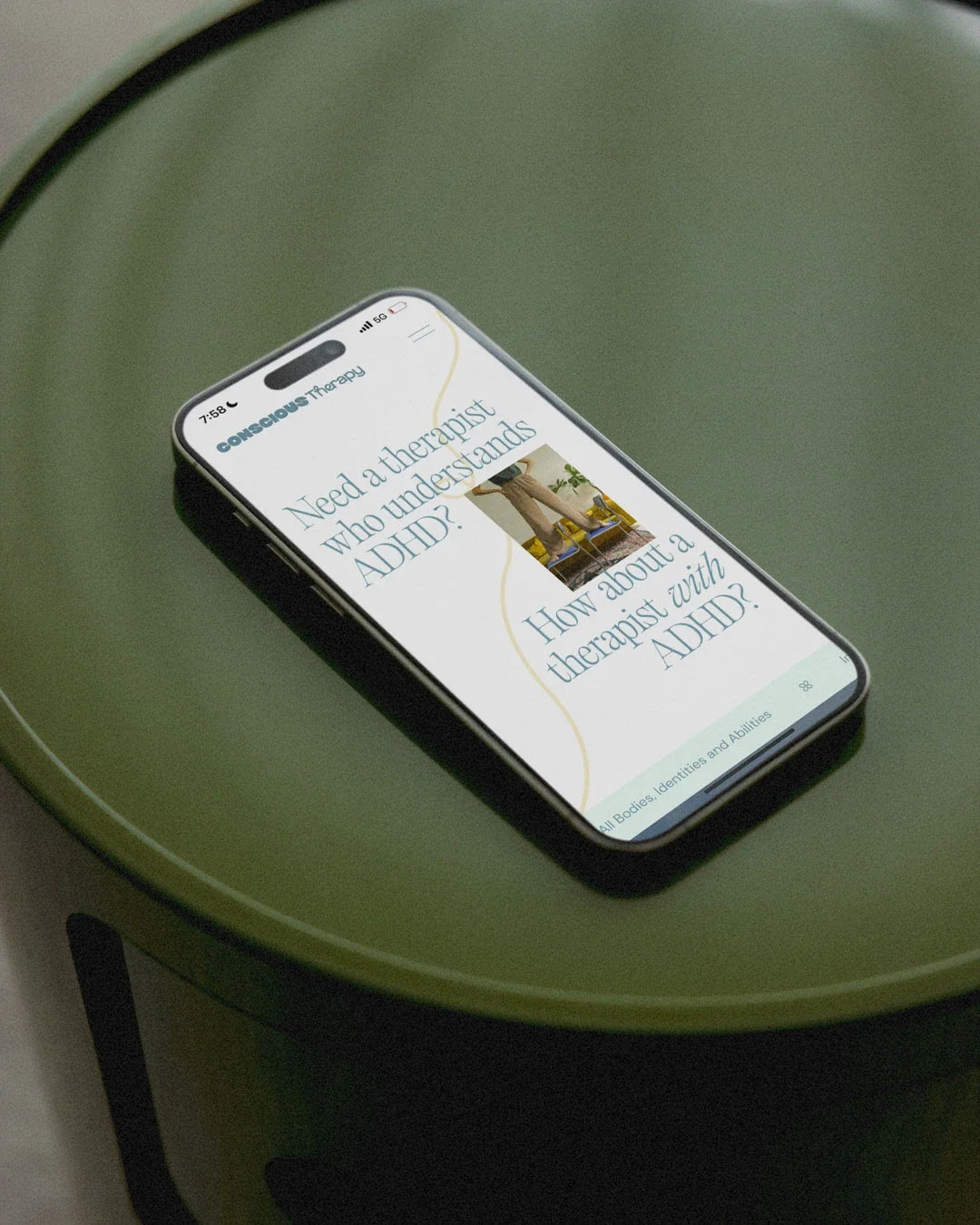 Smartphone displaying a website about therapy and ADHD on a green table.