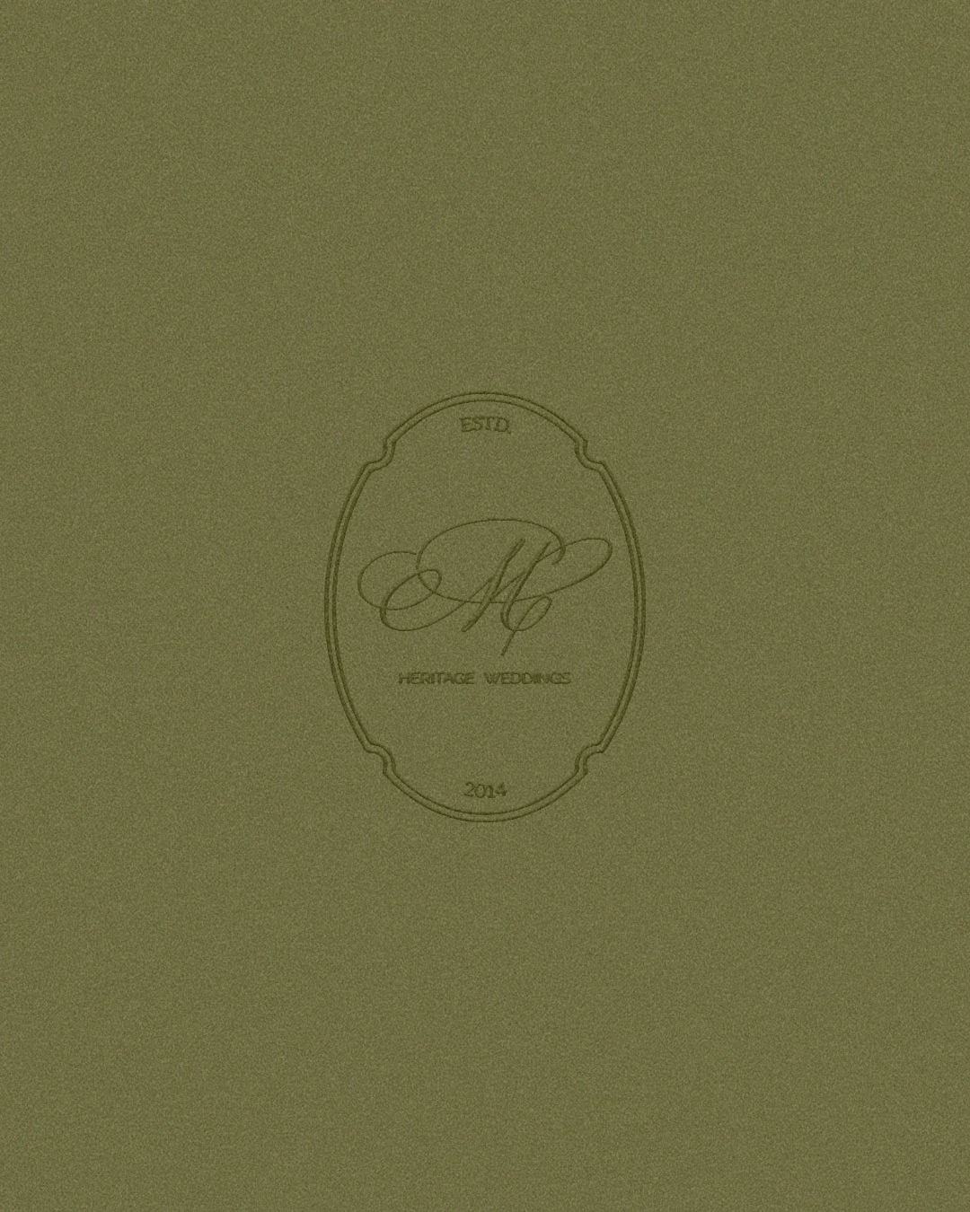A green textured background with a central logo reading 'Heritage Weddings' and the initial 'M' in a decorative script, along with 'ESTD 2014'.