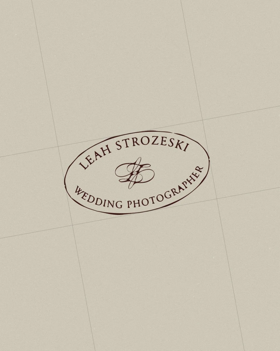 A printed logo with the text 'Leah Strozeski Wedding Photographer', Onassis Web Media's client. The logo is inside an oval shape, with a decorative monogram in the center.