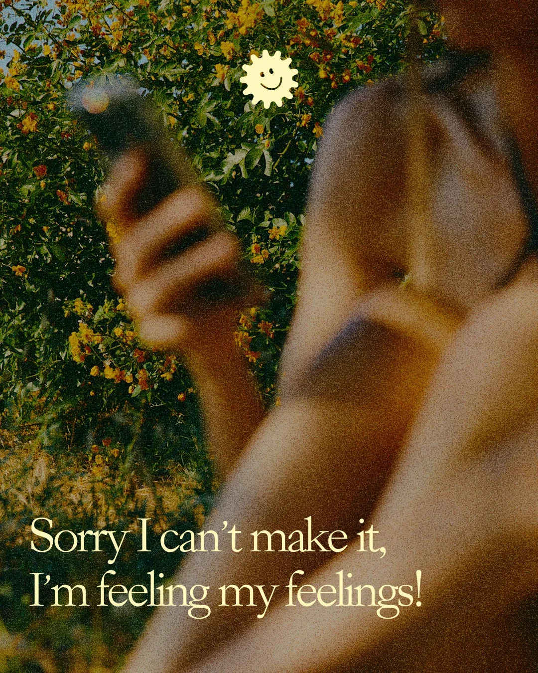 A blurred photo of a person outdoors holding a smartphone, with a background of yellow flowers and green foliage. The text on the image reads, "Sorry I can't make it, I'm feeling my feelings!" and a smiling sun sticker is at the top.