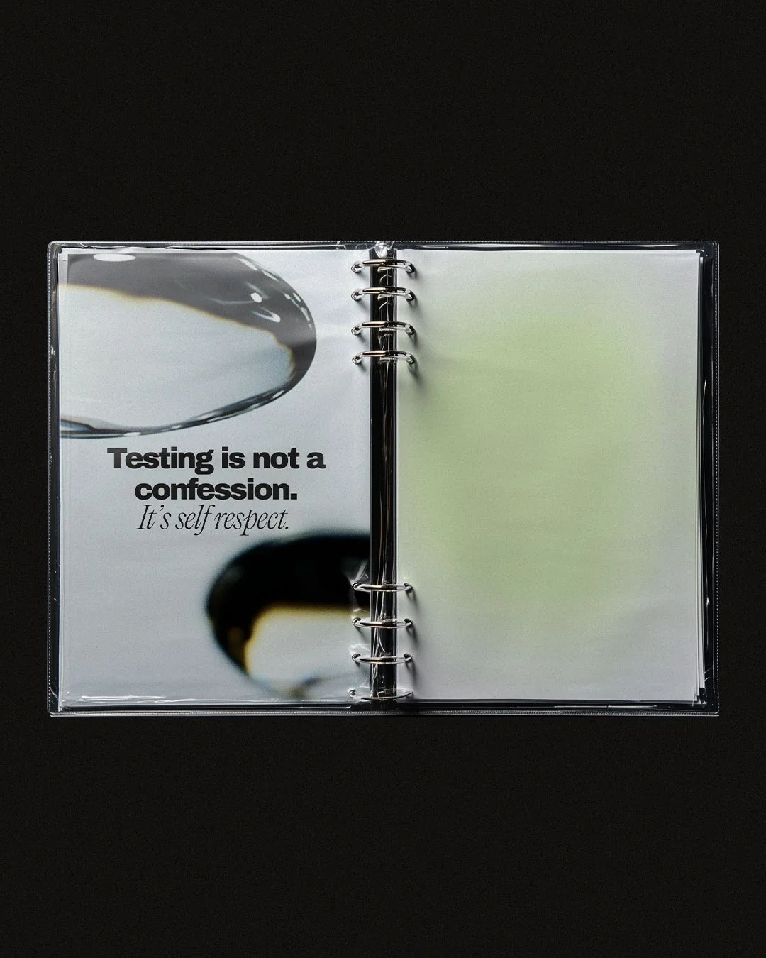 Open binder with a page displaying a quote: 'Testing is not a confession. It's self respect.' with abstract black and white shapes.