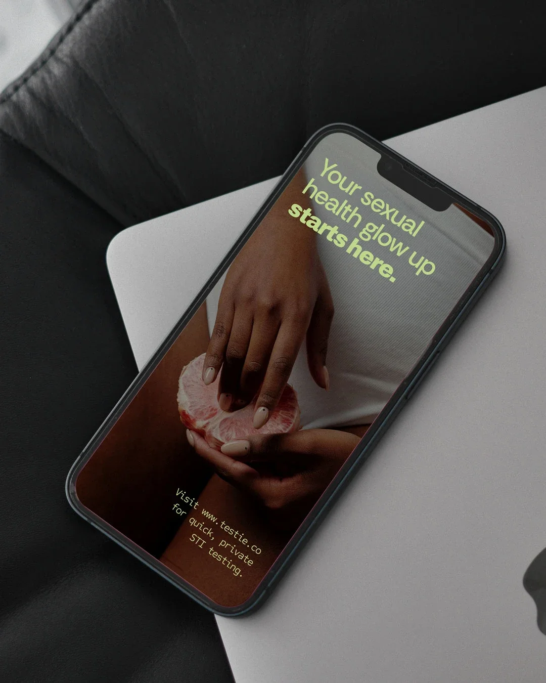 Smartphone displaying a website about sexual health with a background of hands peeling a grapefruit.