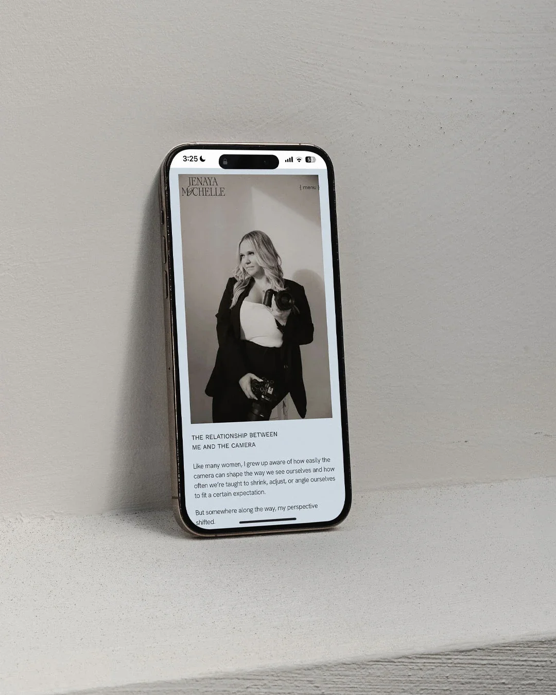 An iPhone displaying a website featuring a black and white photo of a woman holding a camera, with text about the relationship between the woman and the camera.