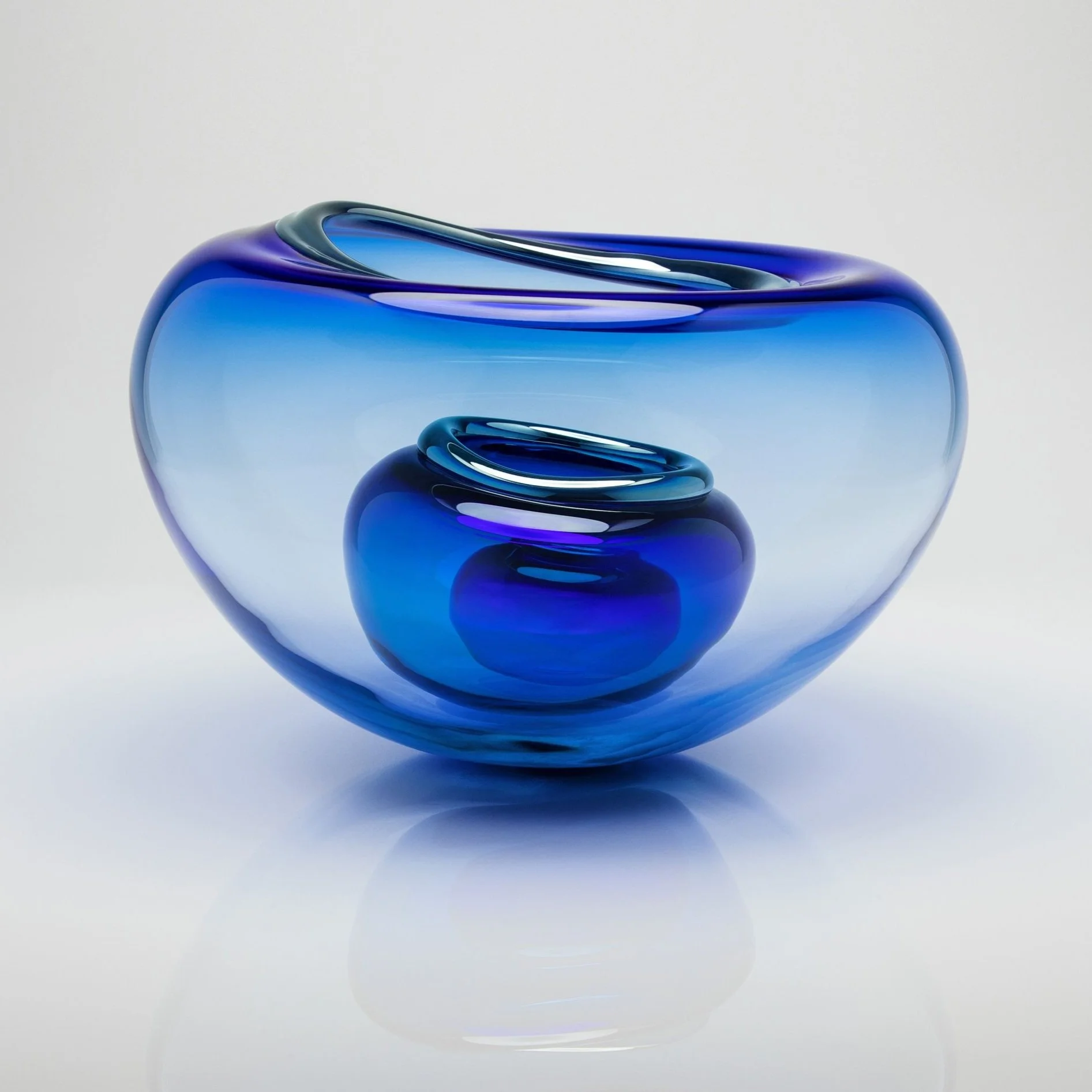 Two nested blue glass vases with swirling patterns, one larger and one smaller, on a white background.