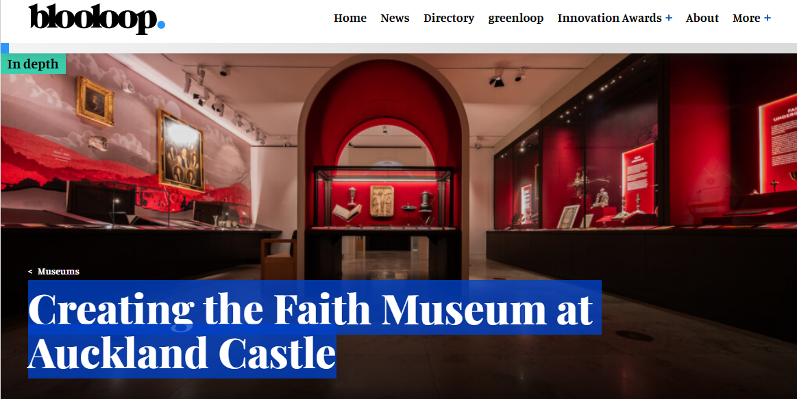 Interior of a museum exhibit with red walls and display cases containing statues and artifacts at Auckland Castle, showcasing religious and historical items.