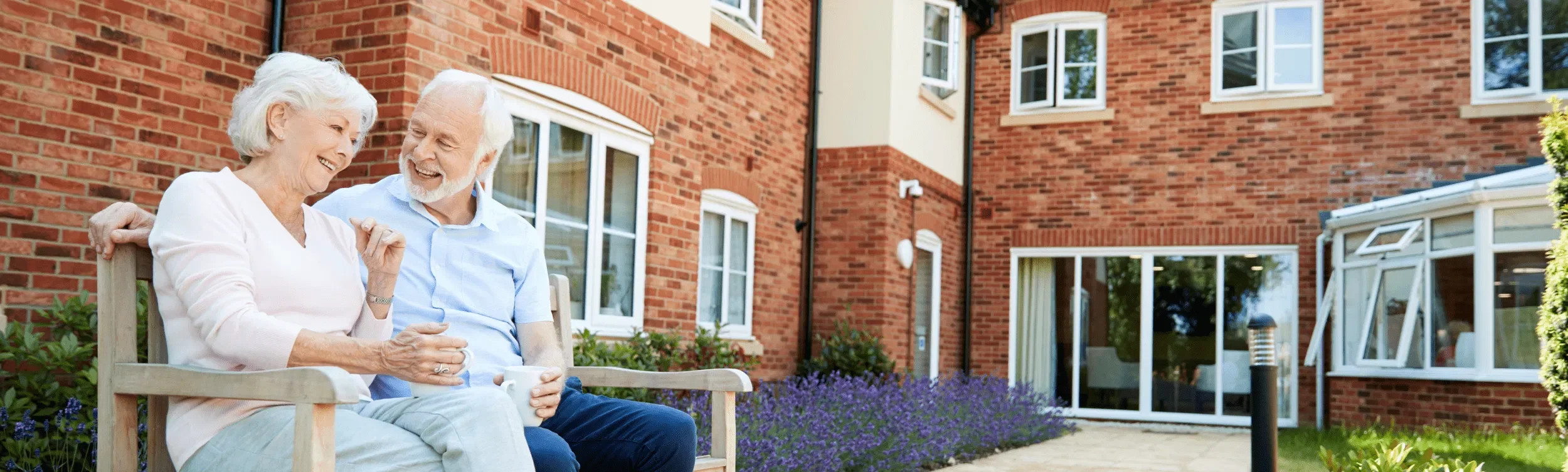 An older couple enjoying tea together outside their new retirement residence, reflecting peace of mind and a smooth transition.