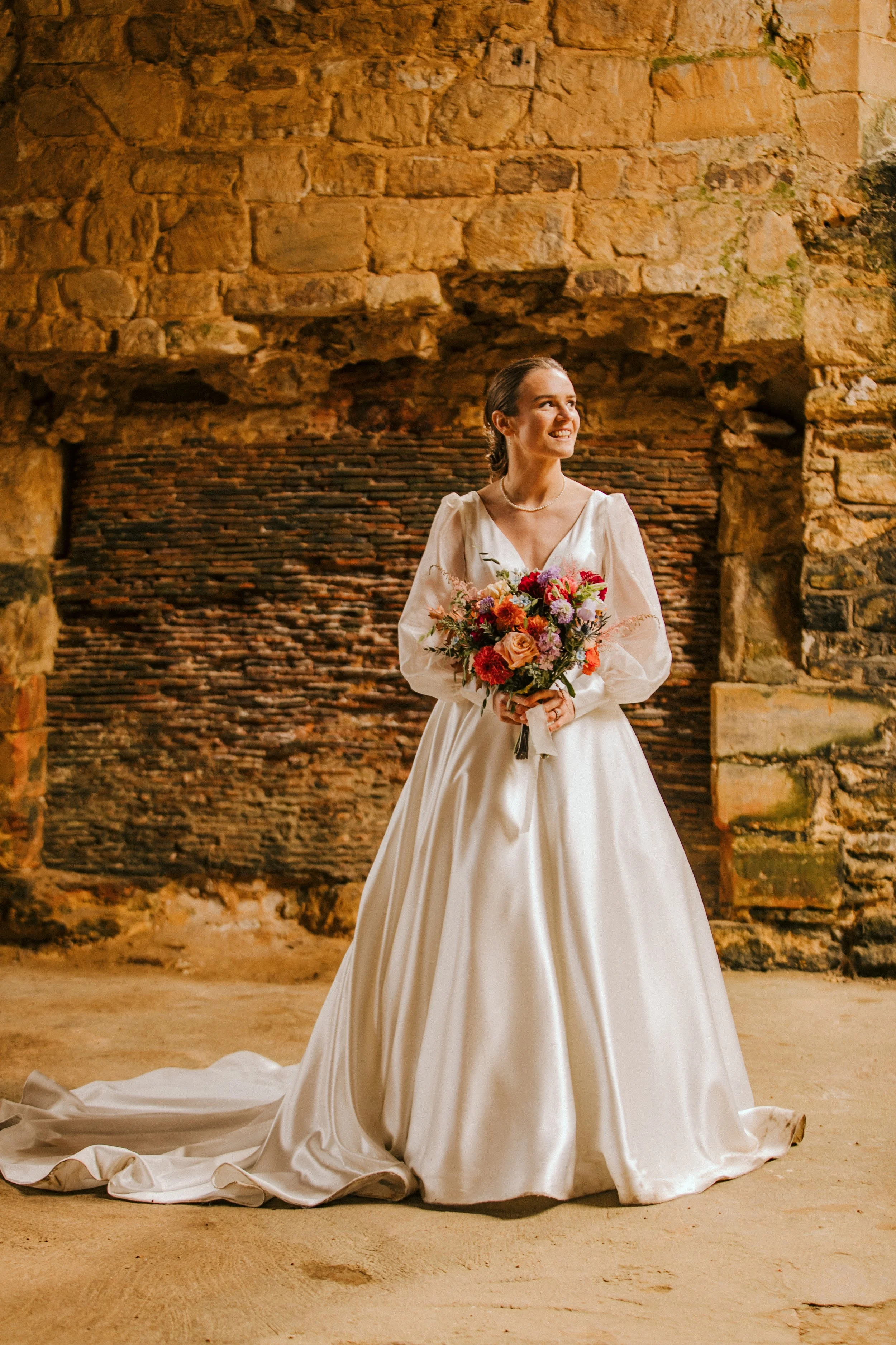 Bride stood in the sunlight of ancient abbey background