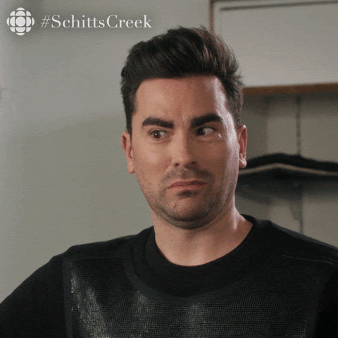 A man making a skeptical face in a room with shelves in the background.