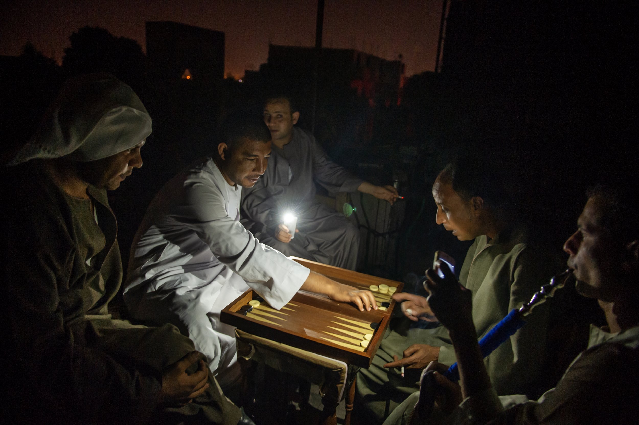  Idle tour guides use their cell phones for light play as they play backgammon at a cafe during a power cut on June 18, 2013 in Luxor, Egypt. Egyptians working in the tourism industry have lost work since the revolution in 2011 and blackouts have bee