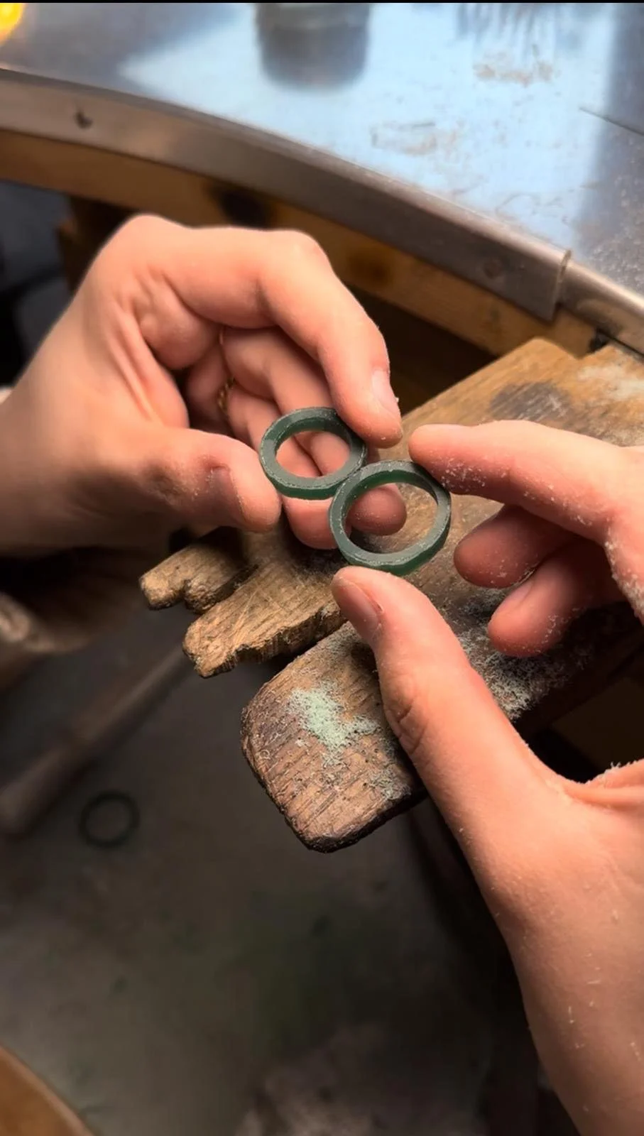 Due mani che lavorano con due anelli di gomma su un banco di legno, sembrare parte di un processo di produzione o di assemblaggio