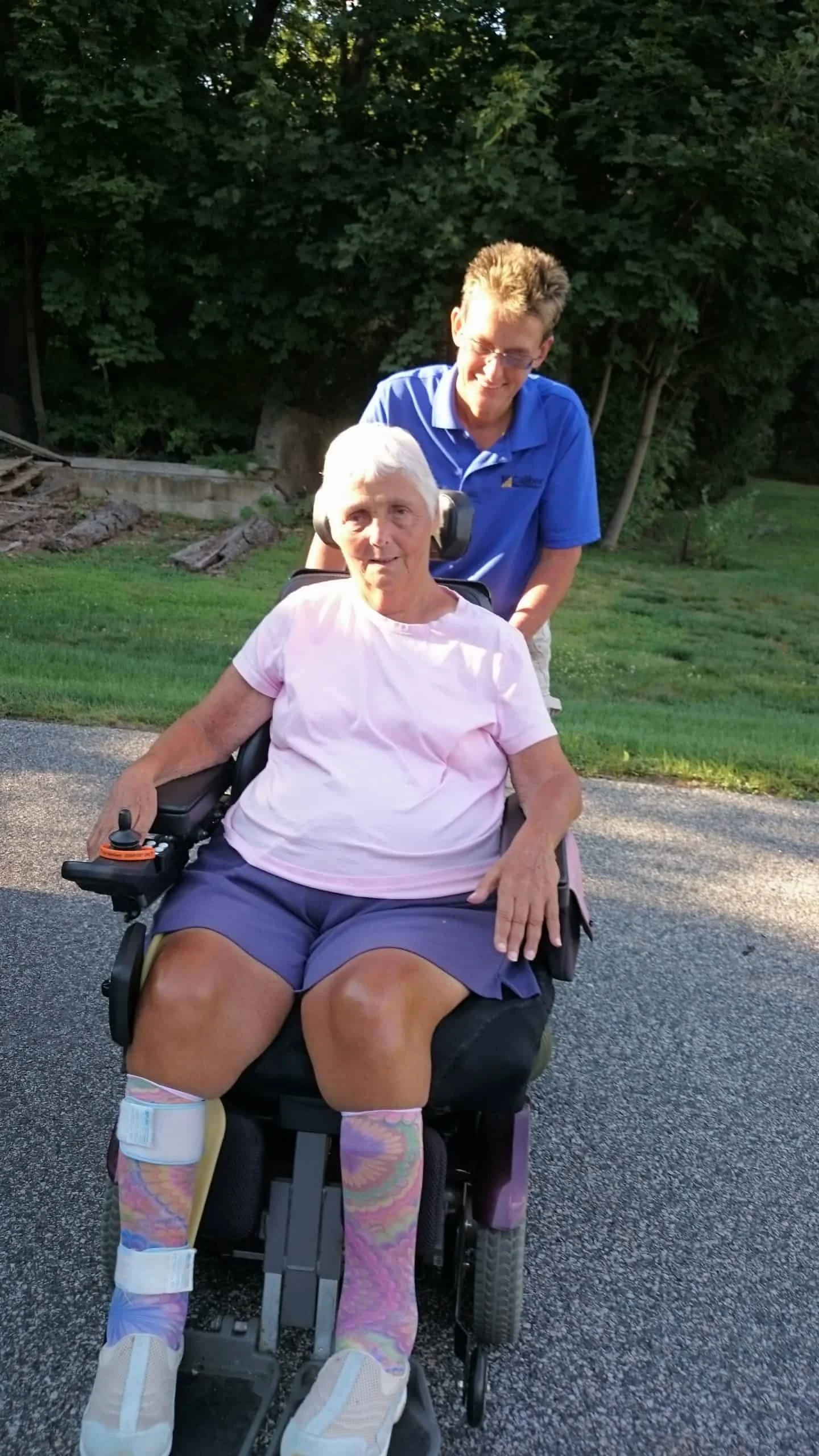 Woman stands with senior woman in electronic wheelchair