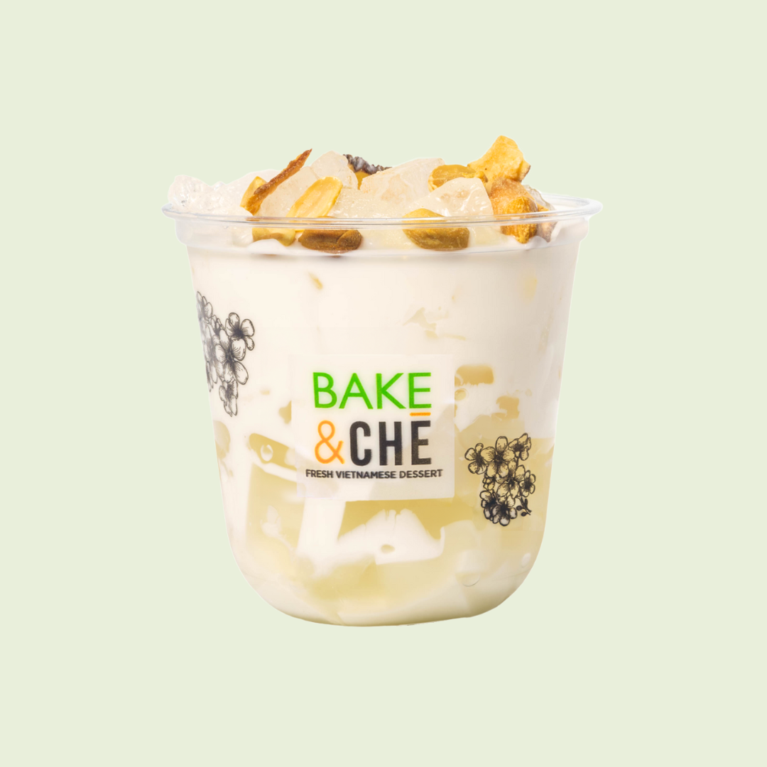 Vietnamese dessert in a transparent cup with a label 'Bake & Che', topped with chopped nuts and coconut flakes, with a light green background.