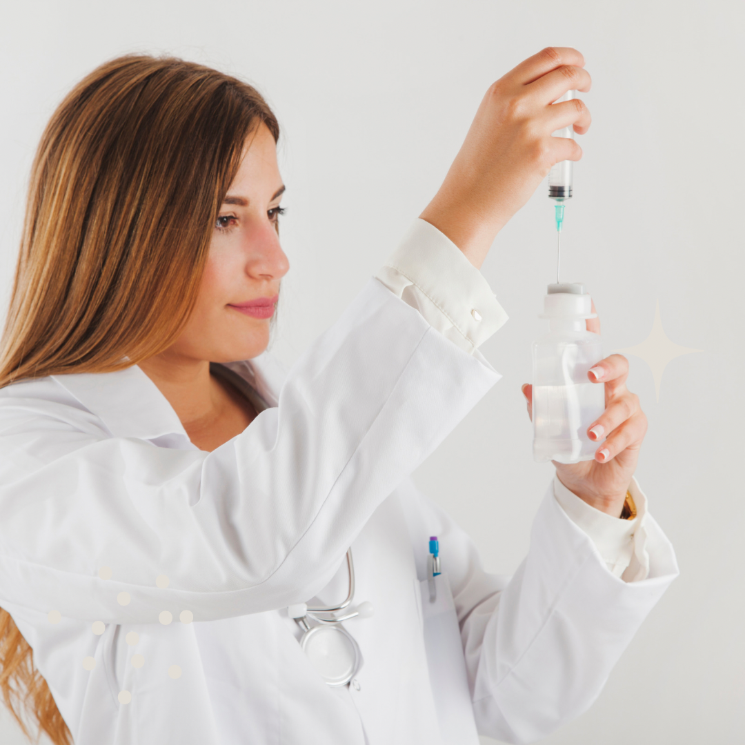 A woman in white carefully fills a syringe from a vial of clear liquid