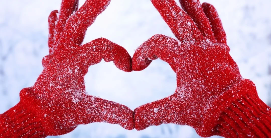 Woman wearing red gloves making a heart with her hands.