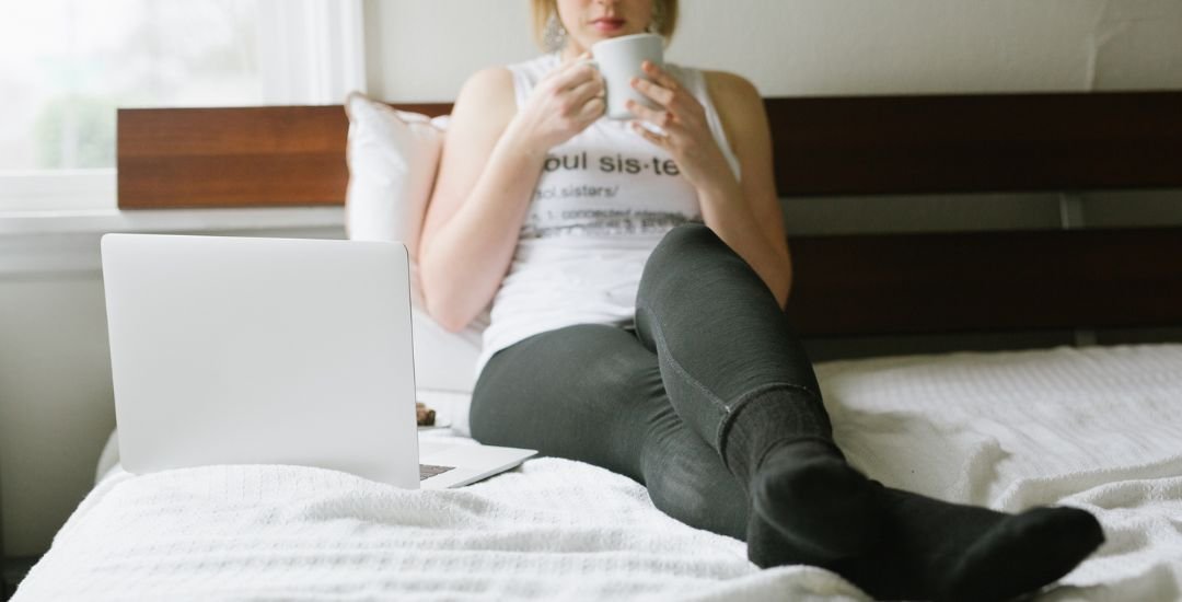 Woman deep in thought sitting on a bed.