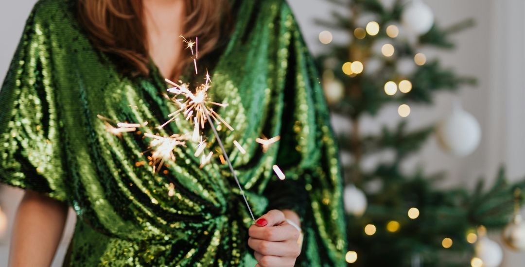 Woman in a green dress, holding a sparkler.