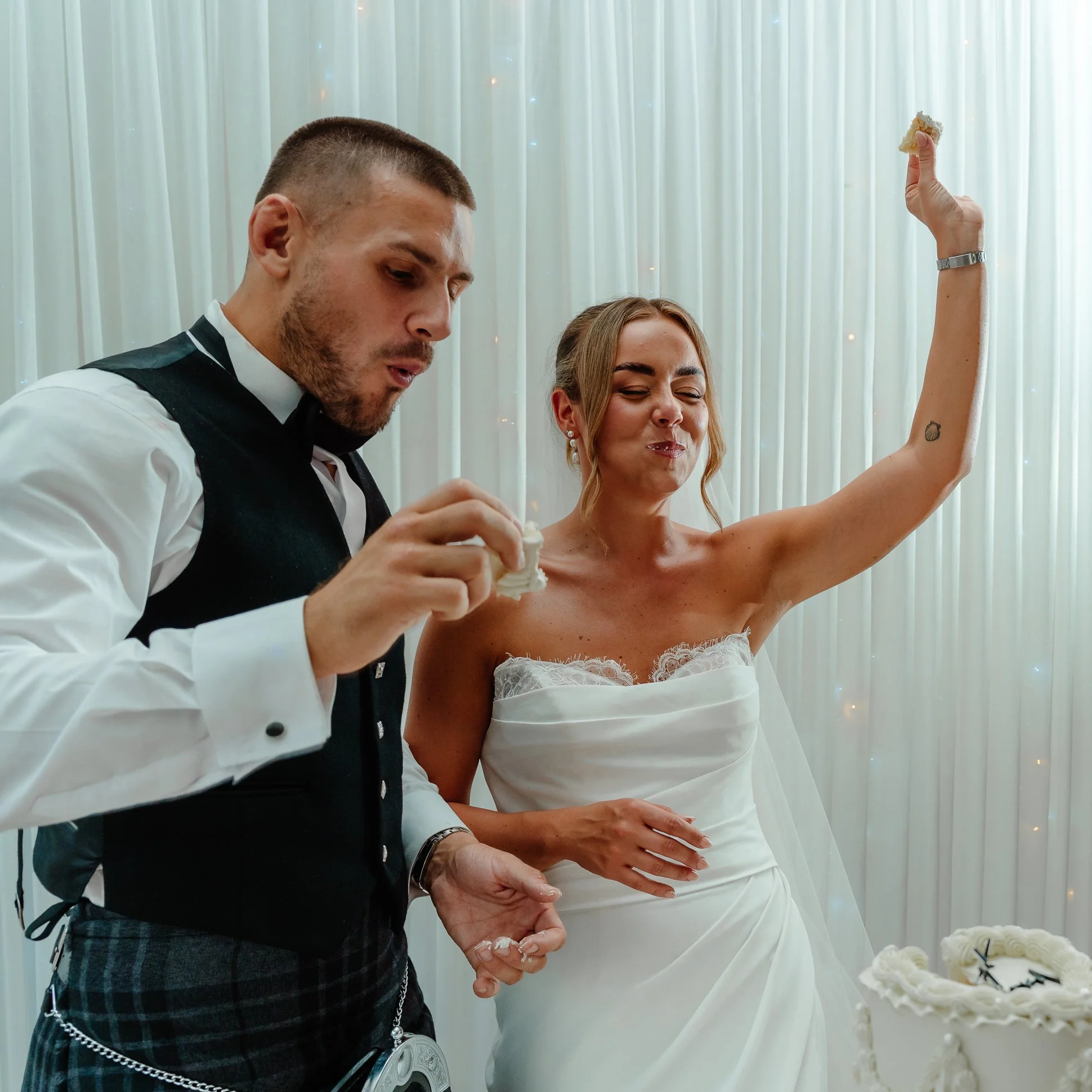 A bride and groom have just cut the cake and are both smiling with mouths full of cake. |It was at the BellaVista restaurant in Littleborough, Greater Manchester.