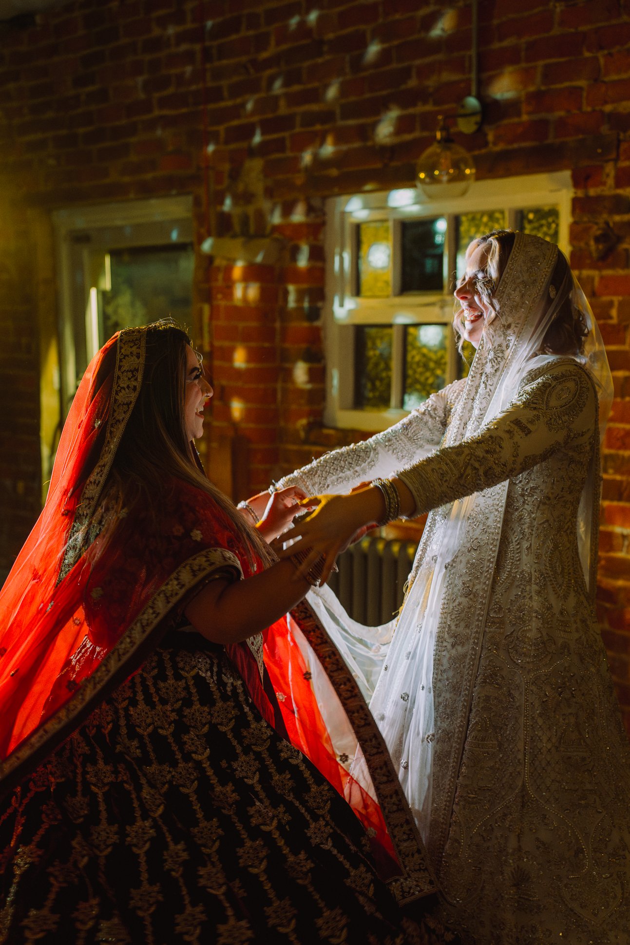 Two brides in traditional Asian lehengas are dancing at their LGBTQ+ wedding in Knutsford, Cheshire