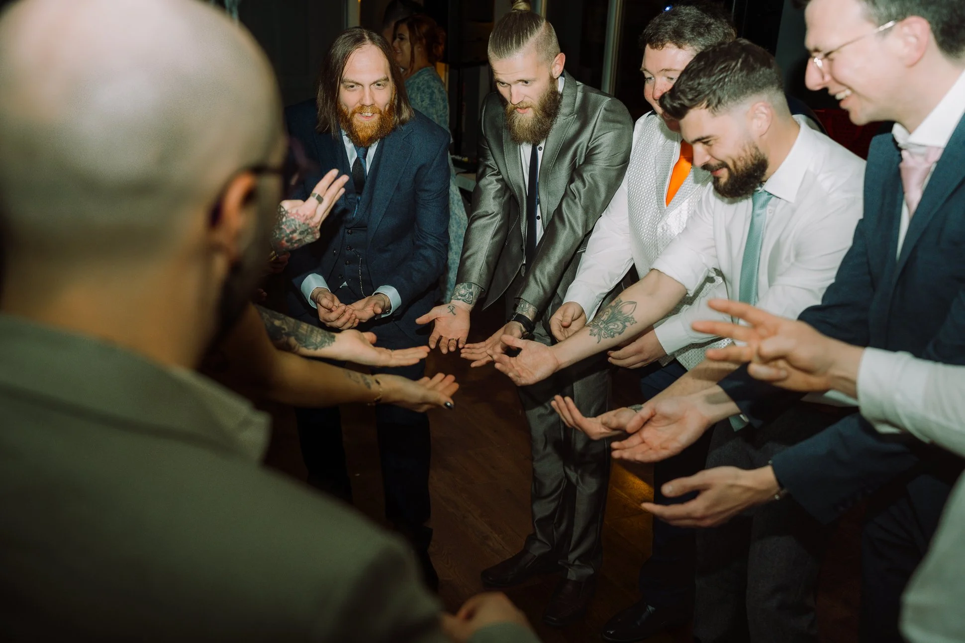 A group of groomsmen are on the dancefloor preparing to lift someone up