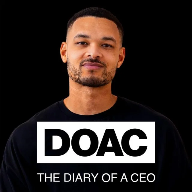 A man with short hair and a light beard wearing a black shirt against a black background, with a white sign that reads 'DOAC: The Diary of a CEO'.