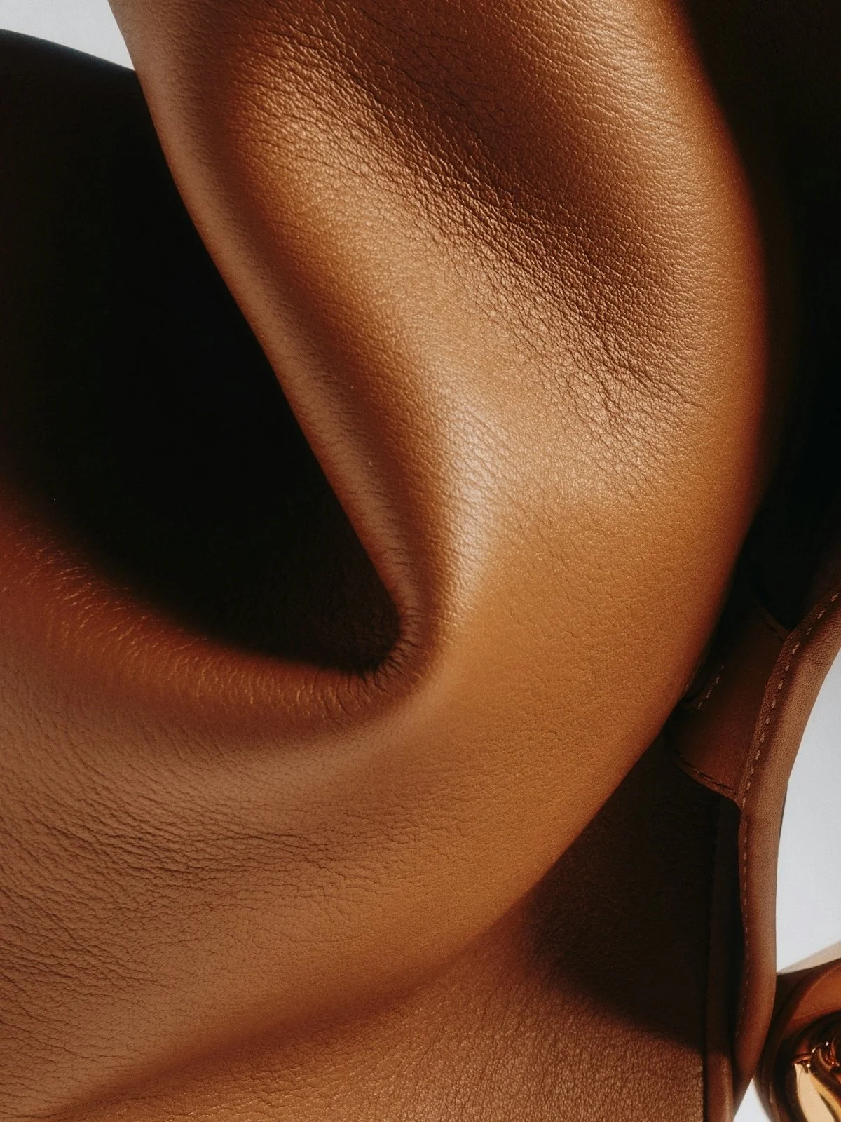 Close-up of brown leather with a smooth, textured surface, showing a folded seam.