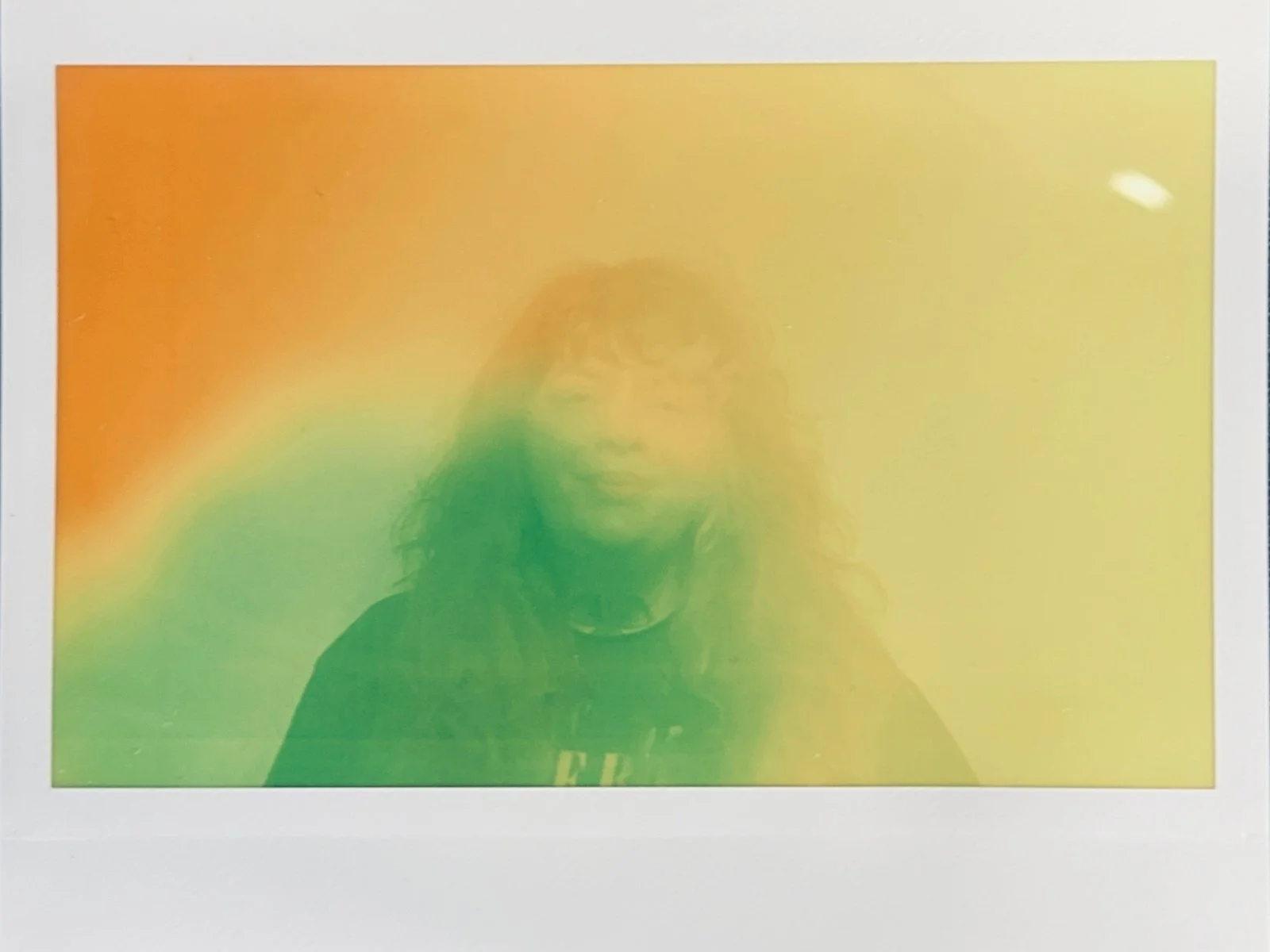 A person taking a selfie with a rainbow-colored filter over the photo, obscuring some facial features.