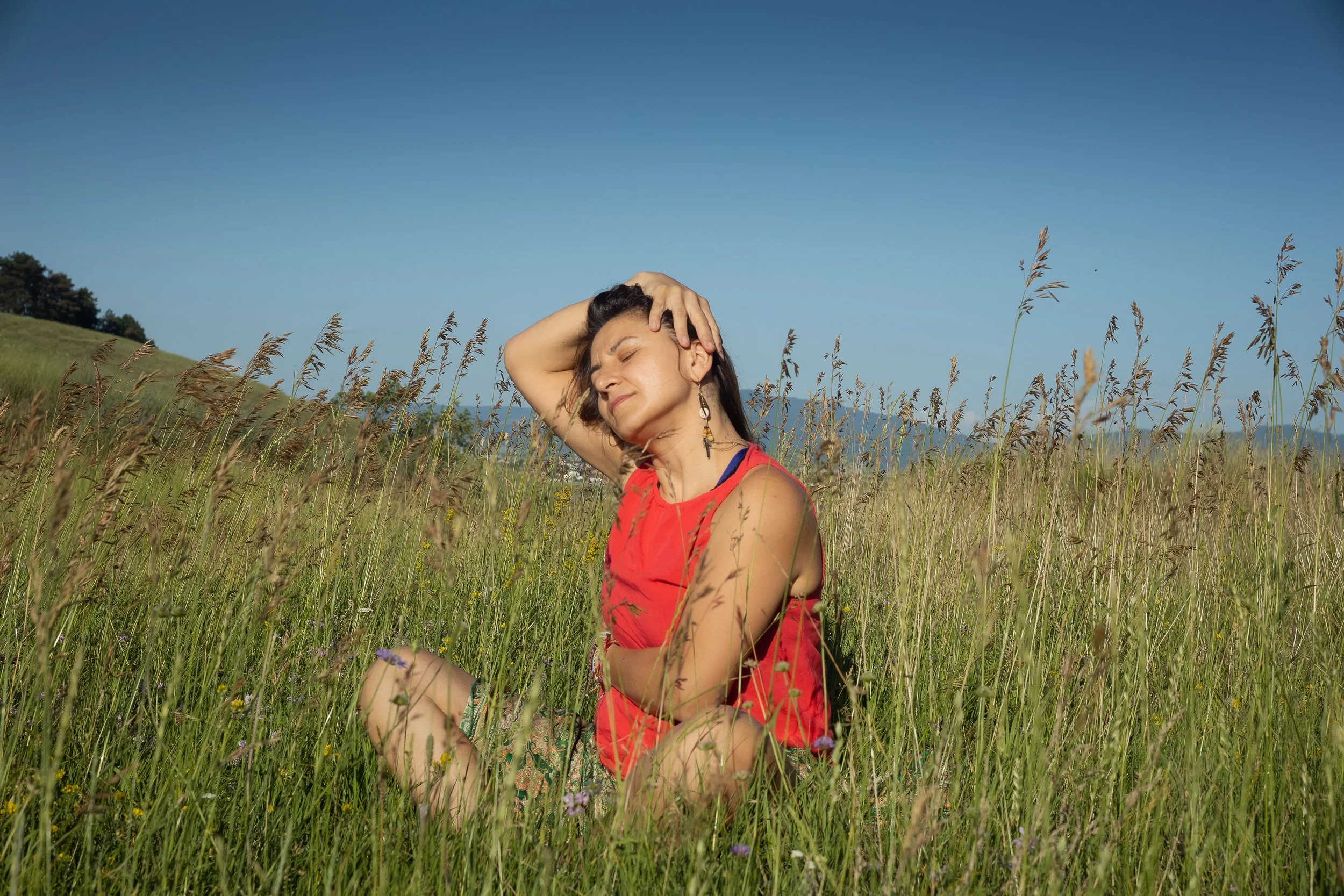 Femeie relaxată într-un câmp cu flori sălbatice, într-un moment de liniște și conectare cu natura.