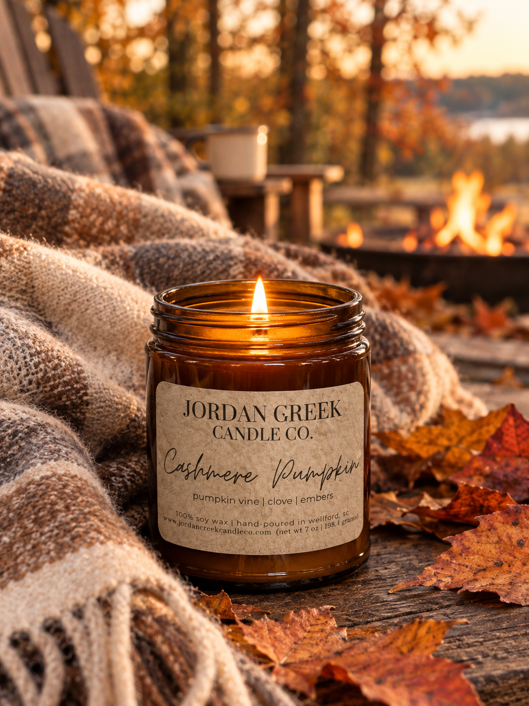cashmere pumpkin candle sitting in front of a cozy flannel blanket