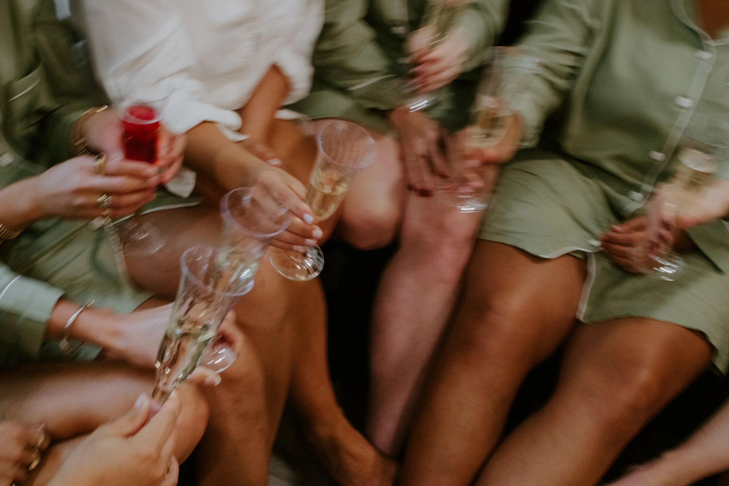 Group of people holding empty glasses at a celebration, with some wearing casual and some more formal clothes, in an indoor setting.