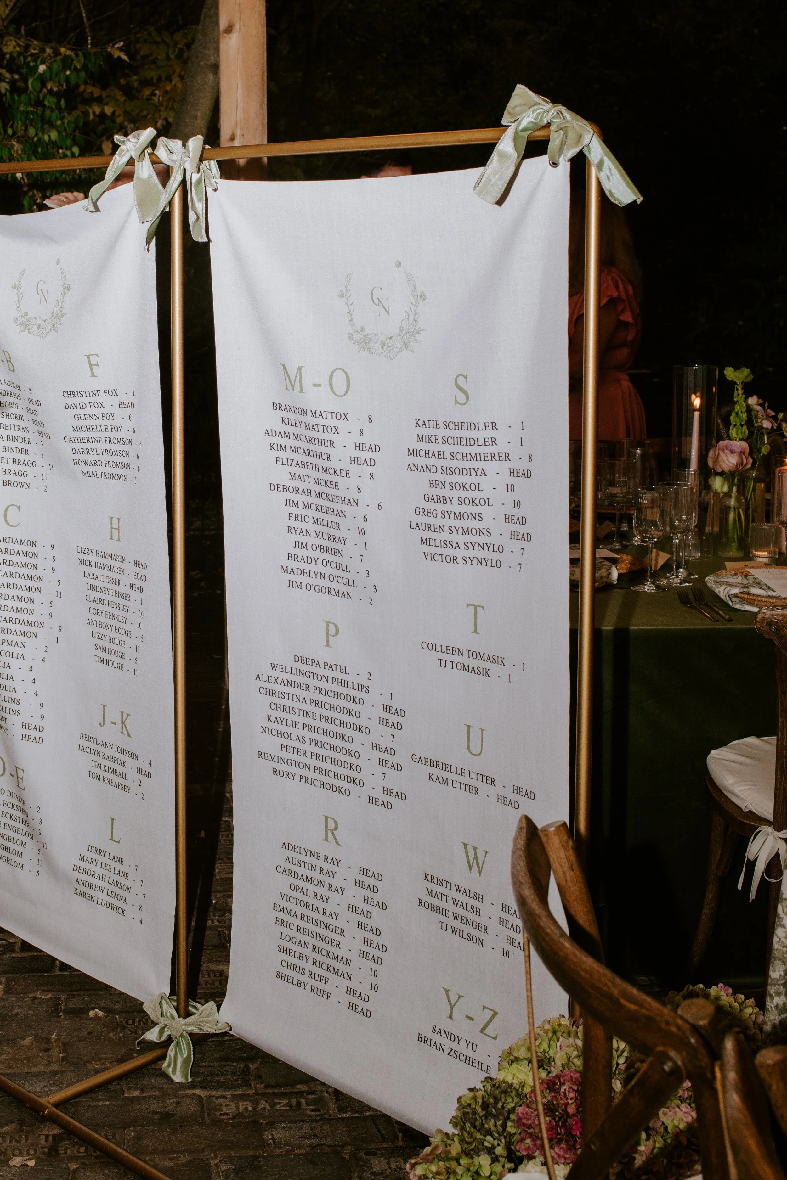 Outdoor wedding seating chart with names arranged alphabetically, decorated with bows and flowers