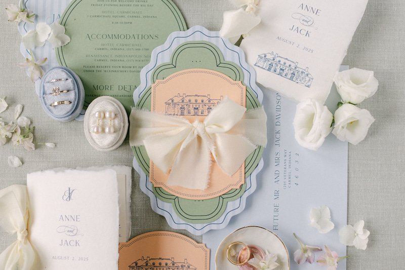 Wedding stationery set in soft blues and greens paired with wedding rings and earrings