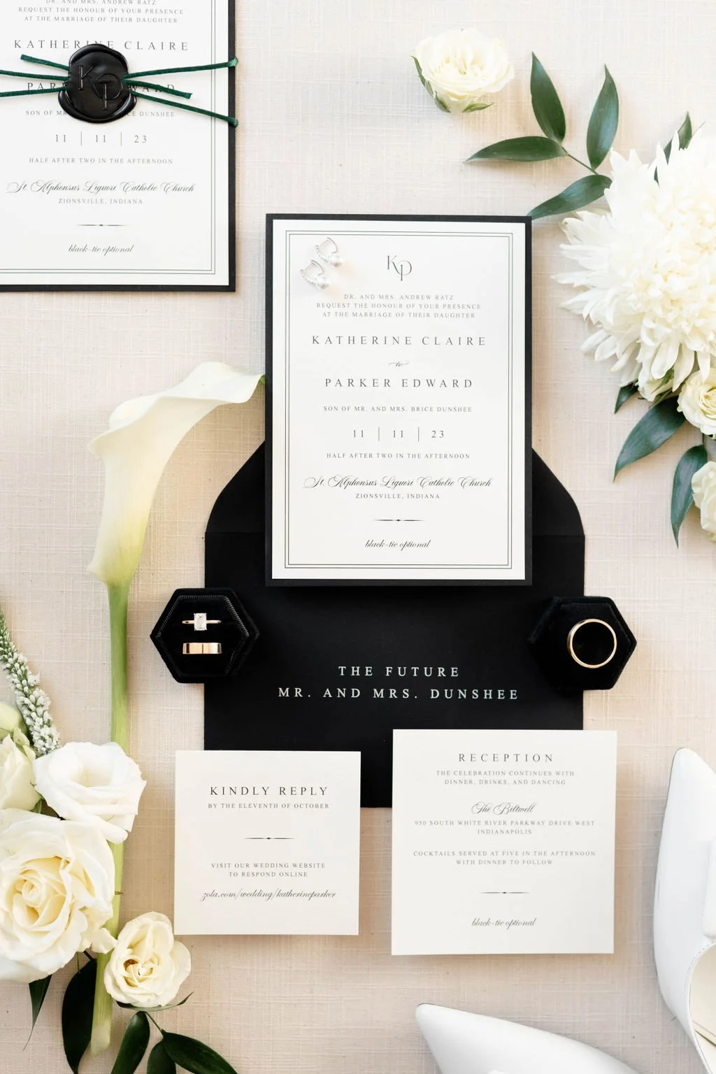 Elegant wedding invitation suite displayed with floral accents, rings, and jewelry.