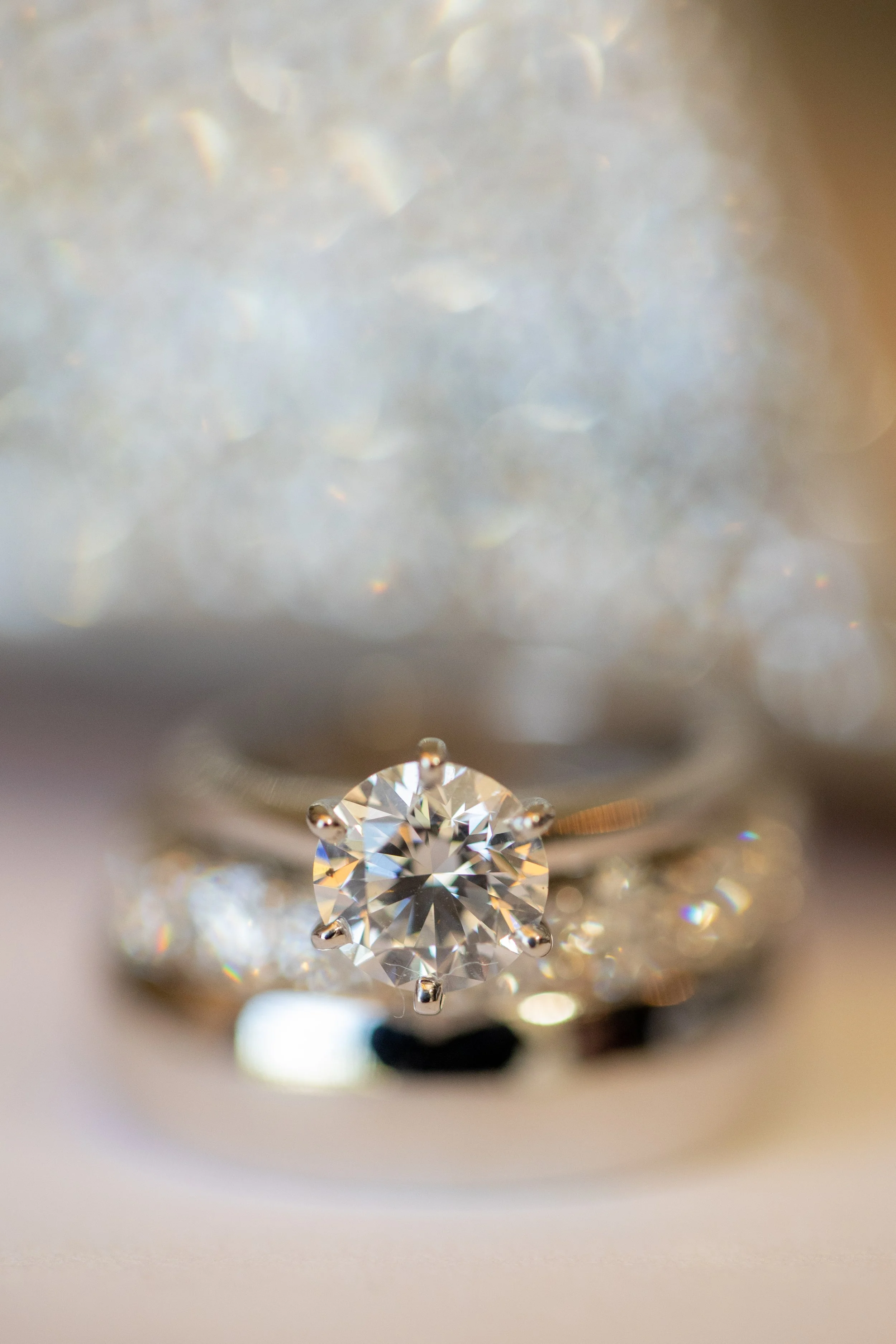 Close-up of a single round diamond solitaire engagement ring set in a white metal band, taken through a magnifying glass or jeweler's loupe.
