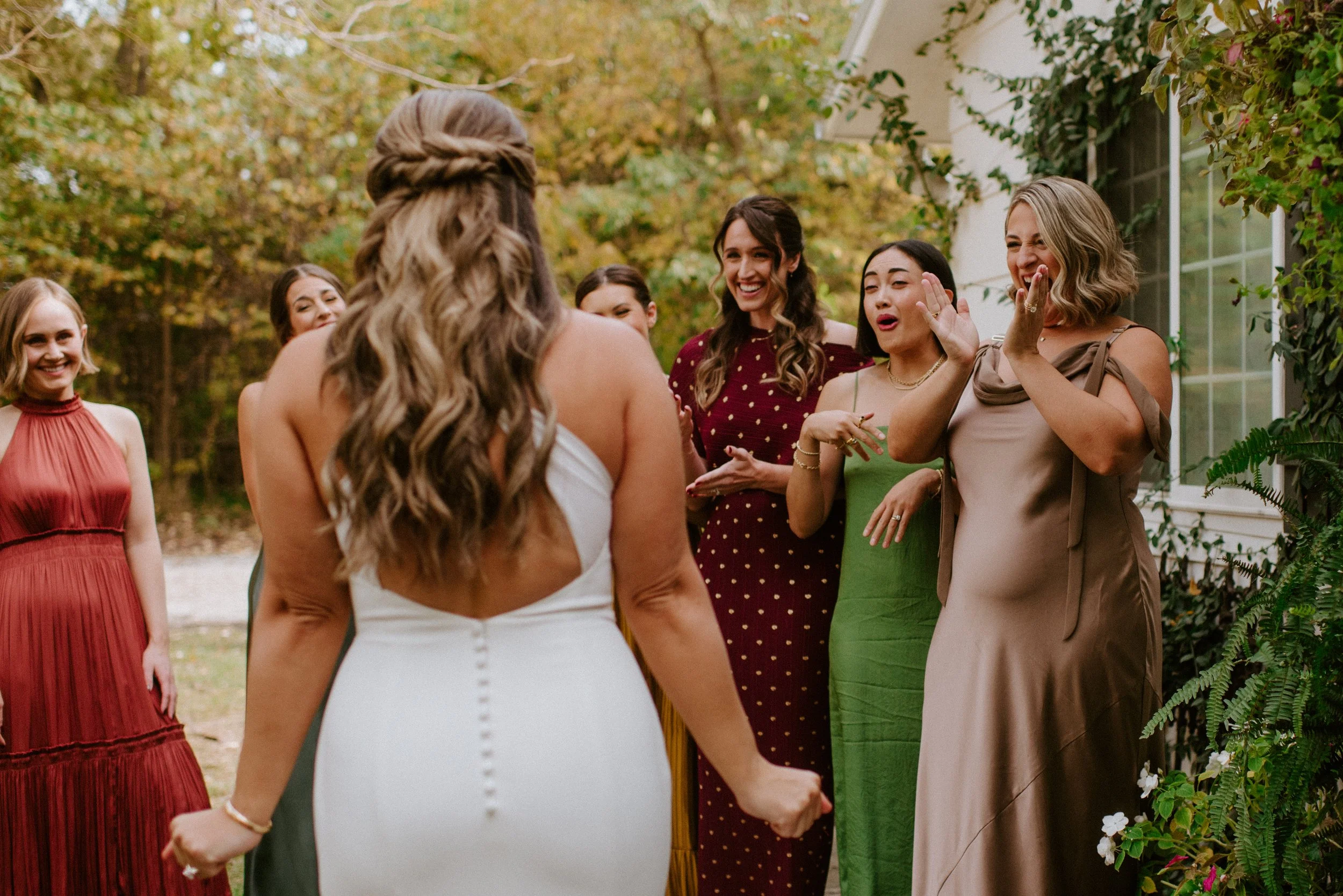 Women in colorful dresses laughing and talking outside during fall.