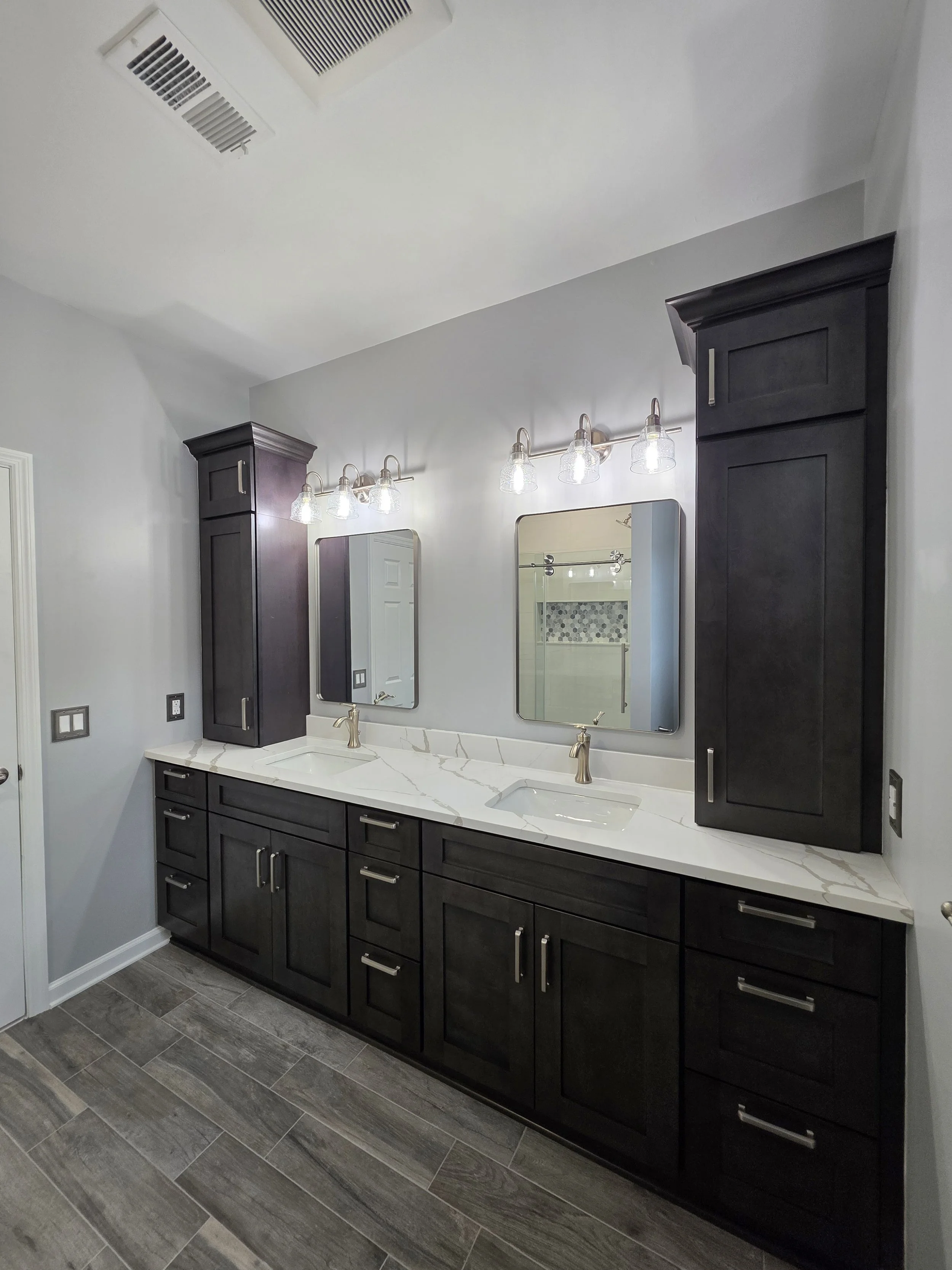 Master bathroom vanity with tall storage and gray flooring.