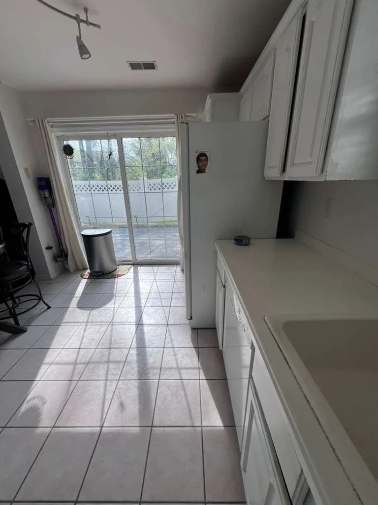 Before renovation: the original kitchen cabinets and square tile floor beside the sliding door.