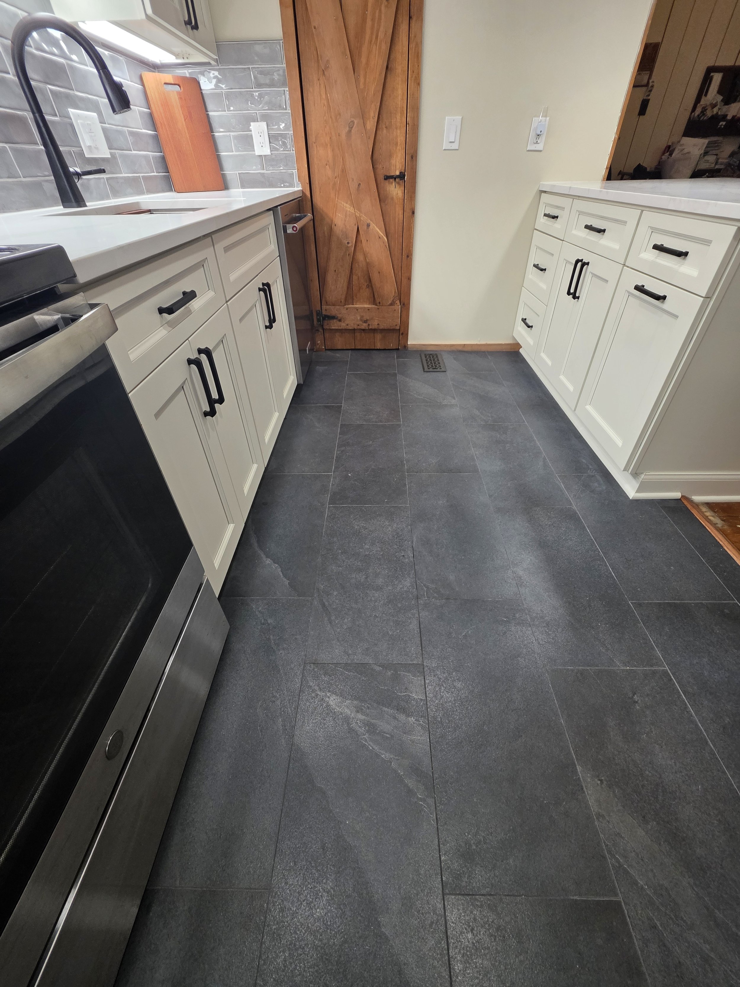 Low view of the dark kitchen floor between the sink cabinets and peninsula.