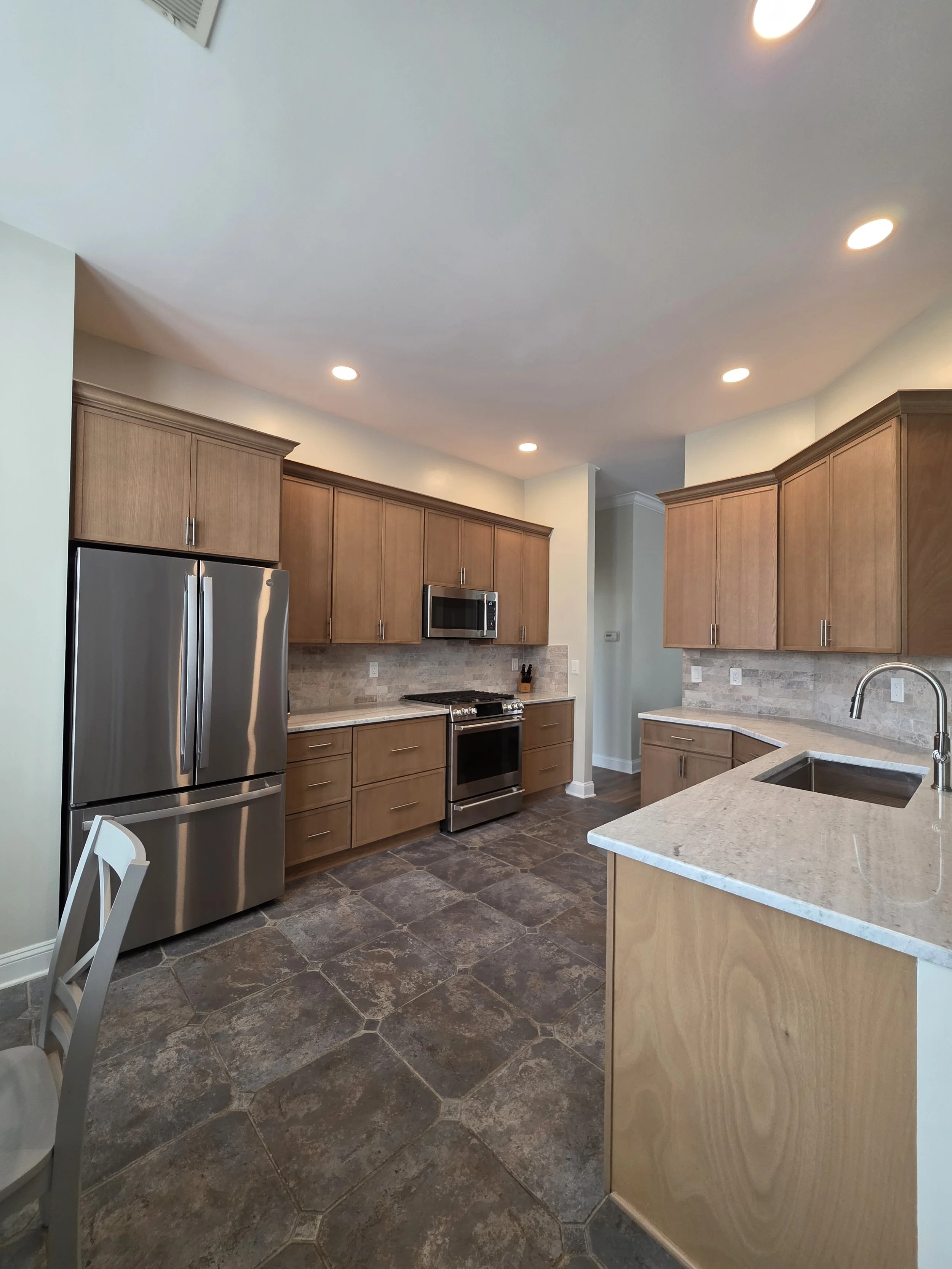 Lou and Elaine’s remodeled kitchen with wood cabinetry, a peninsula sink and stainless appliances.