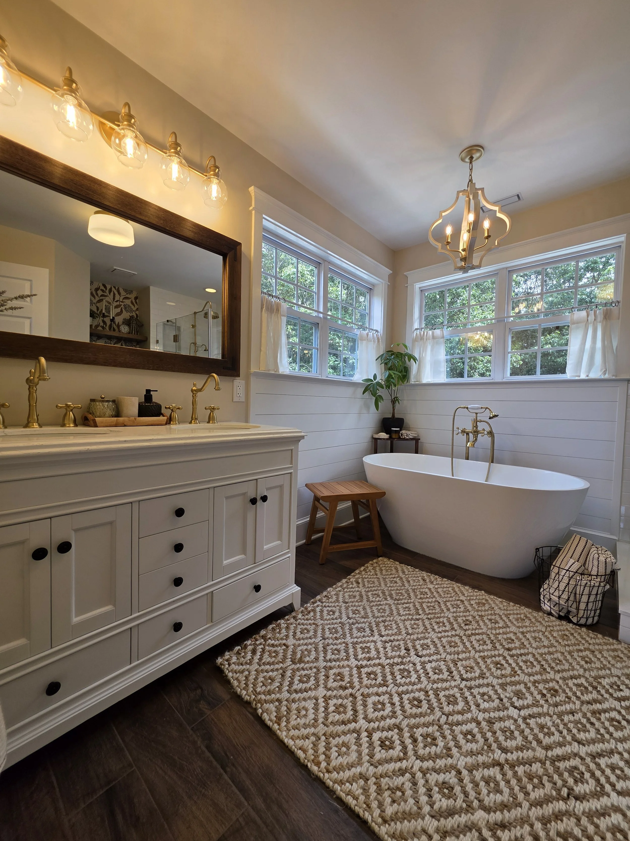 Vanity and tub beneath decorative lighting.