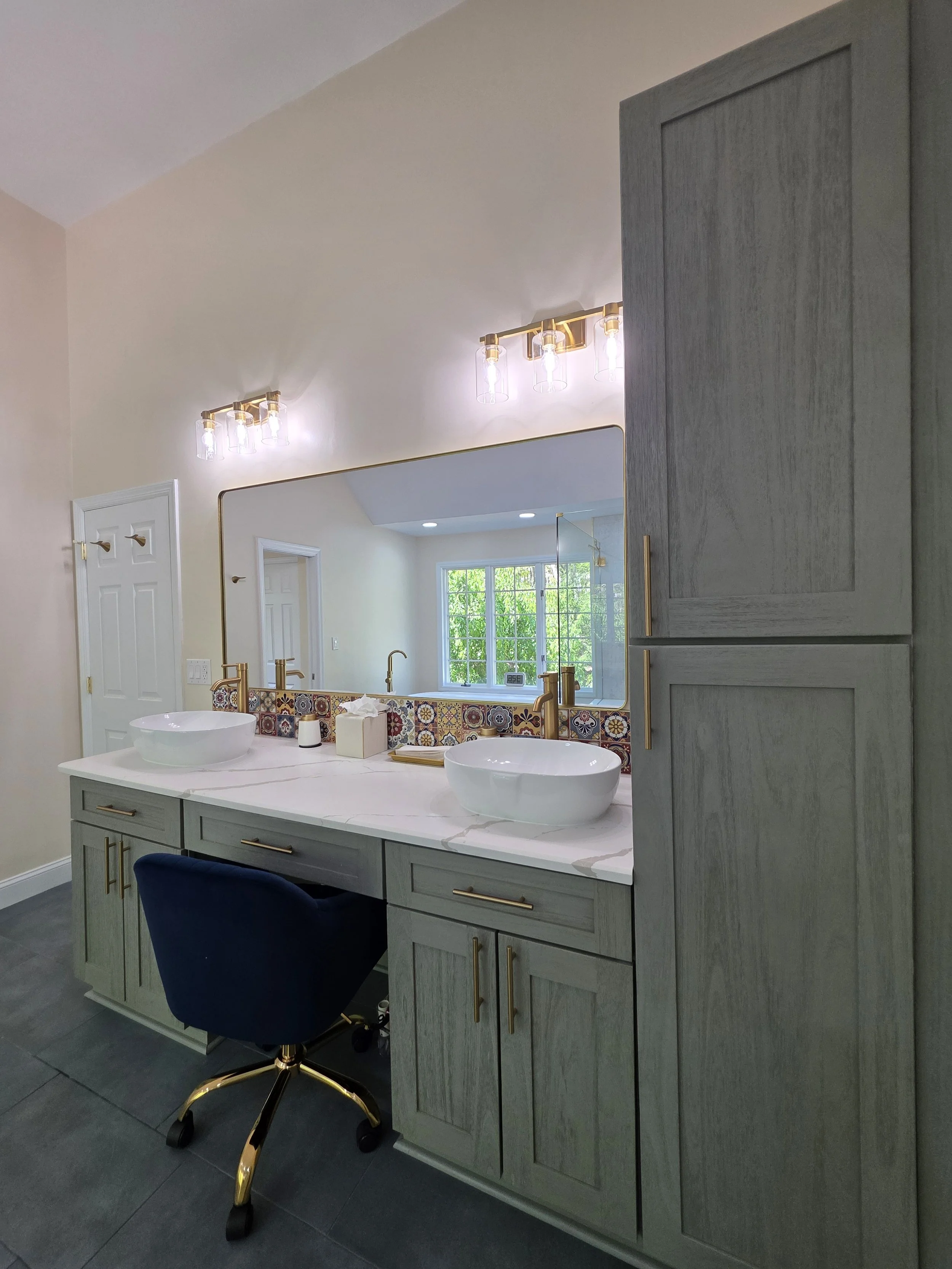 Woodgrain double vanity with white vessel sinks, gold-tone faucets and a large wall mirror.