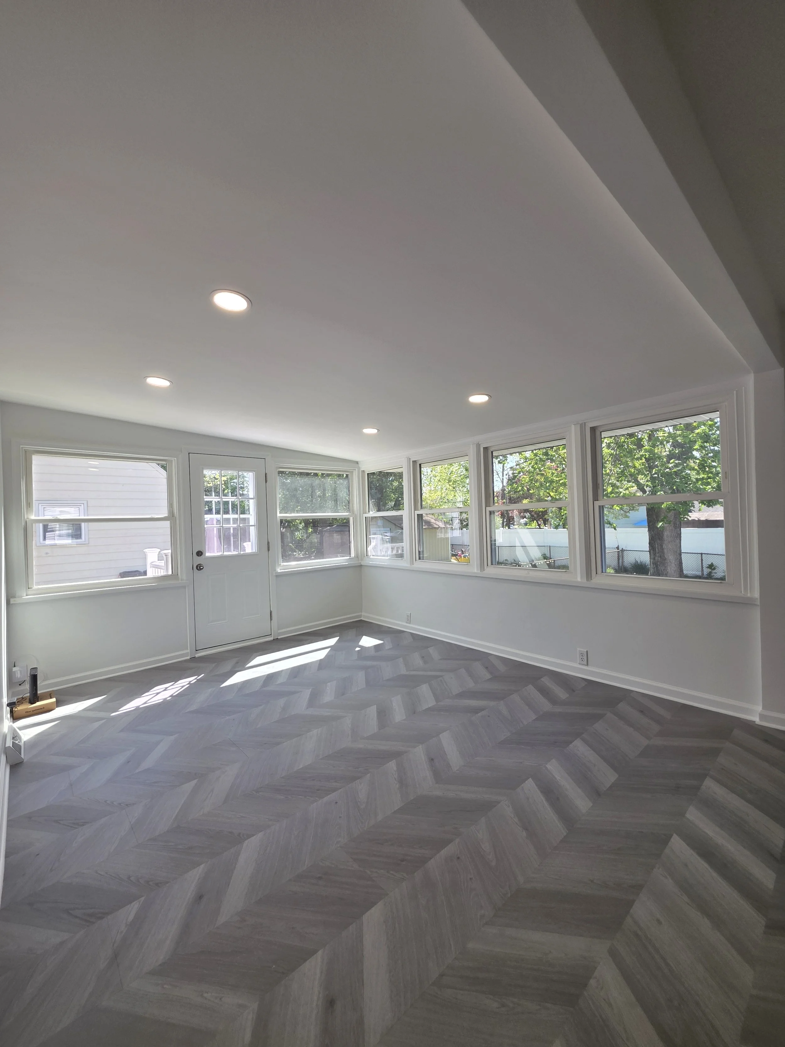 Samuel’s refreshed living space with herringbone-pattern flooring, pale walls and bright windows.