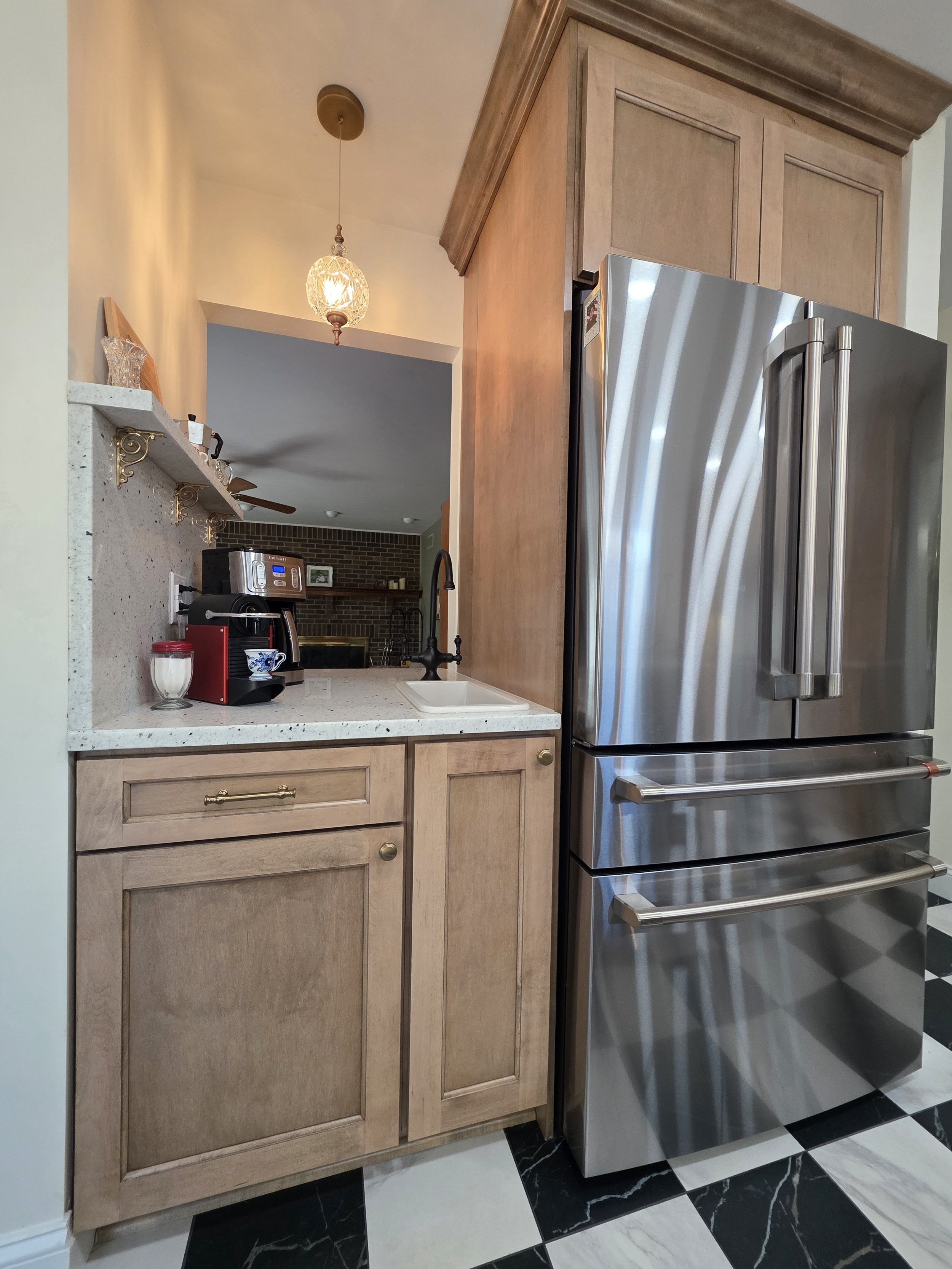 Stainless refrigerator within tall wood cabinetry beside a small counter area.